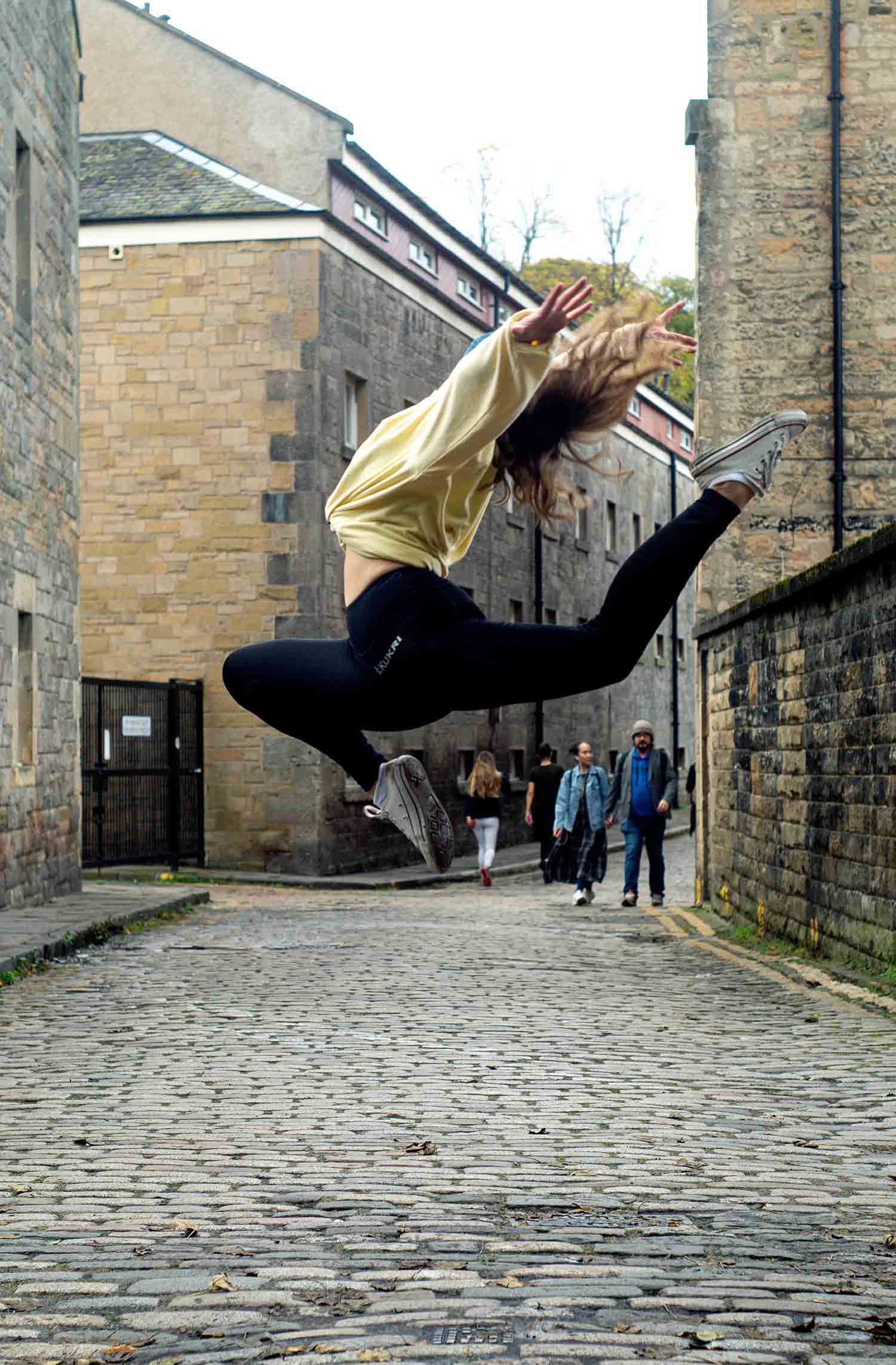 A gymnast jumping in a side street