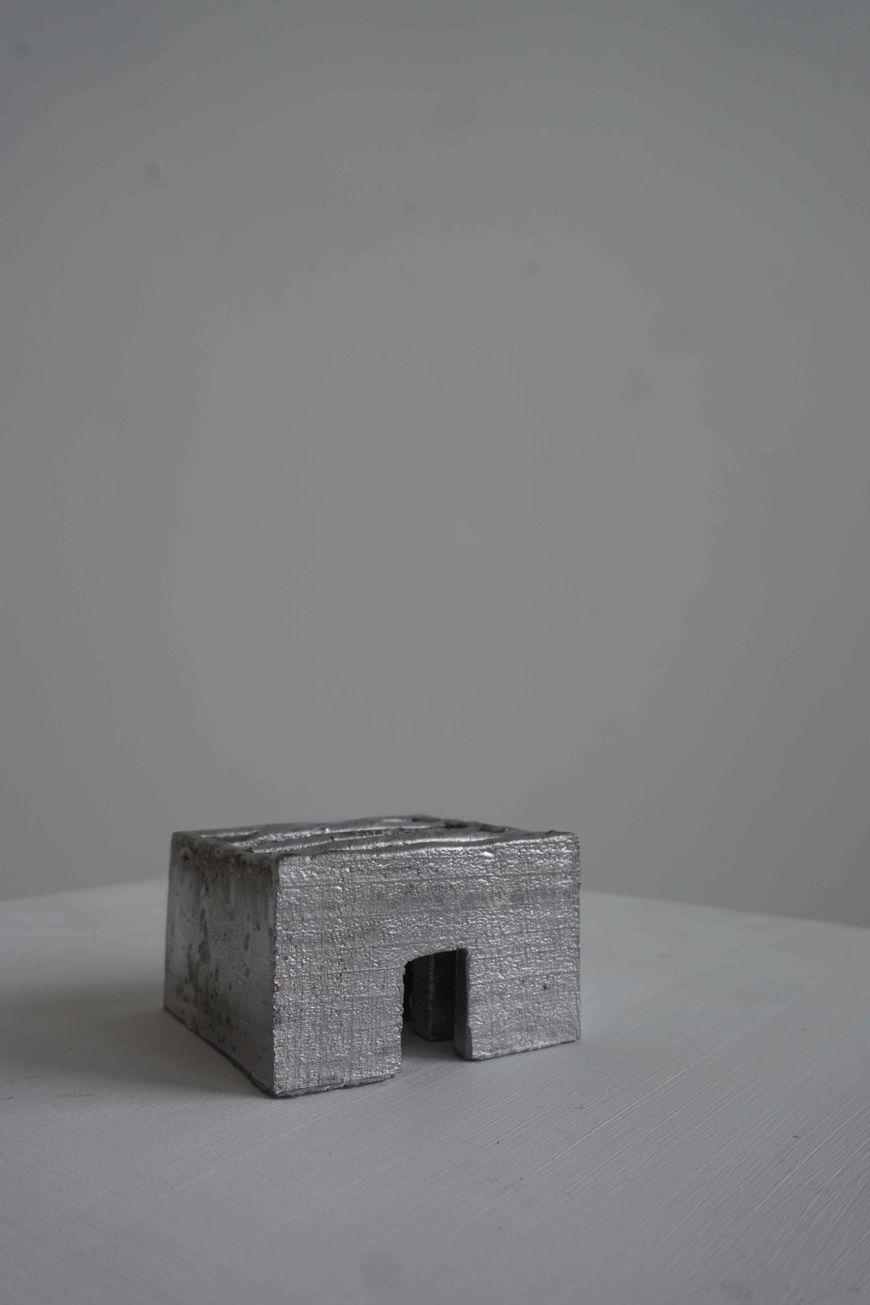 Small cast lead sculpture, consisting of a small room divided many times with walls and doors.