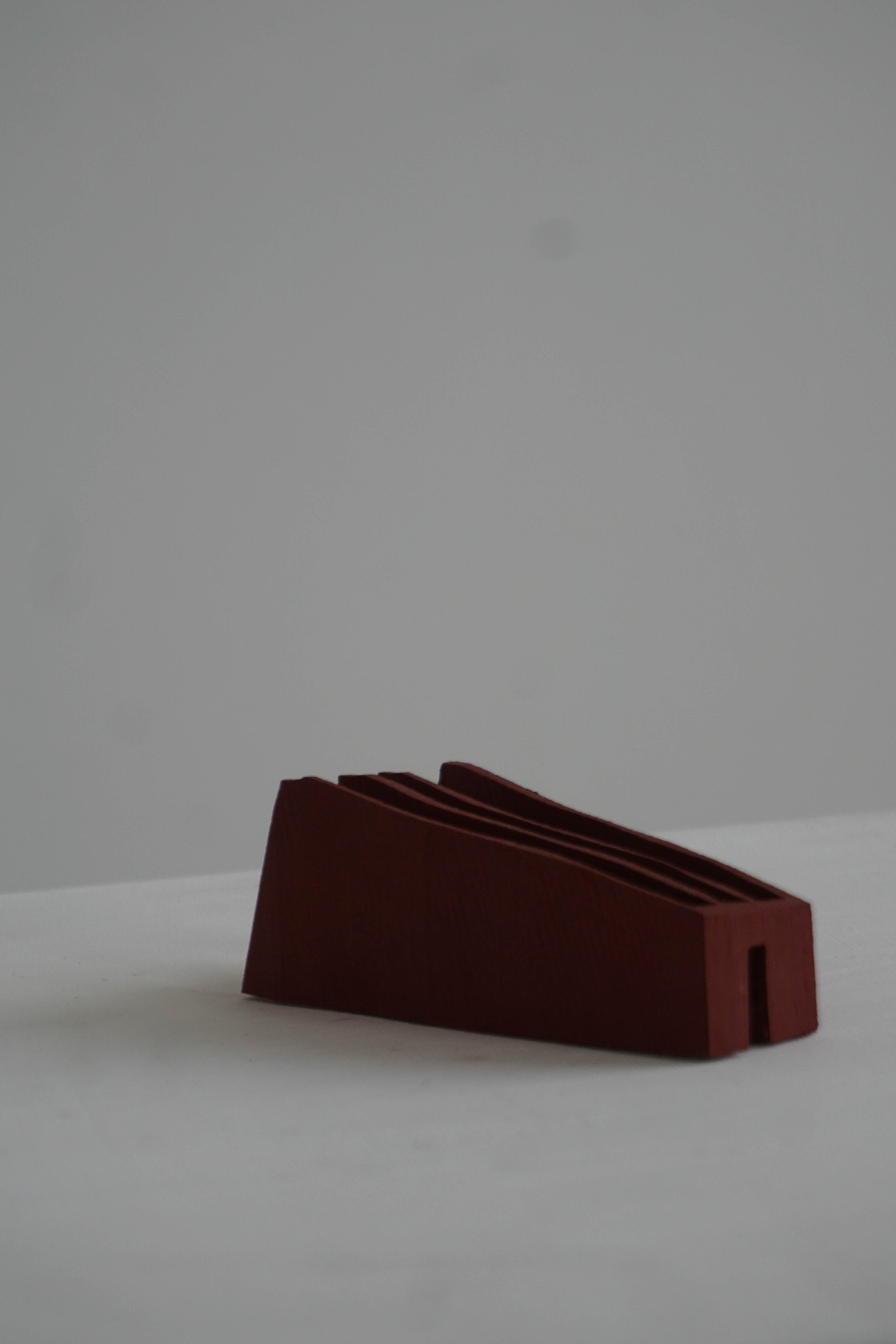 small sculpture painted red, looking even smaller in a large empty void. 