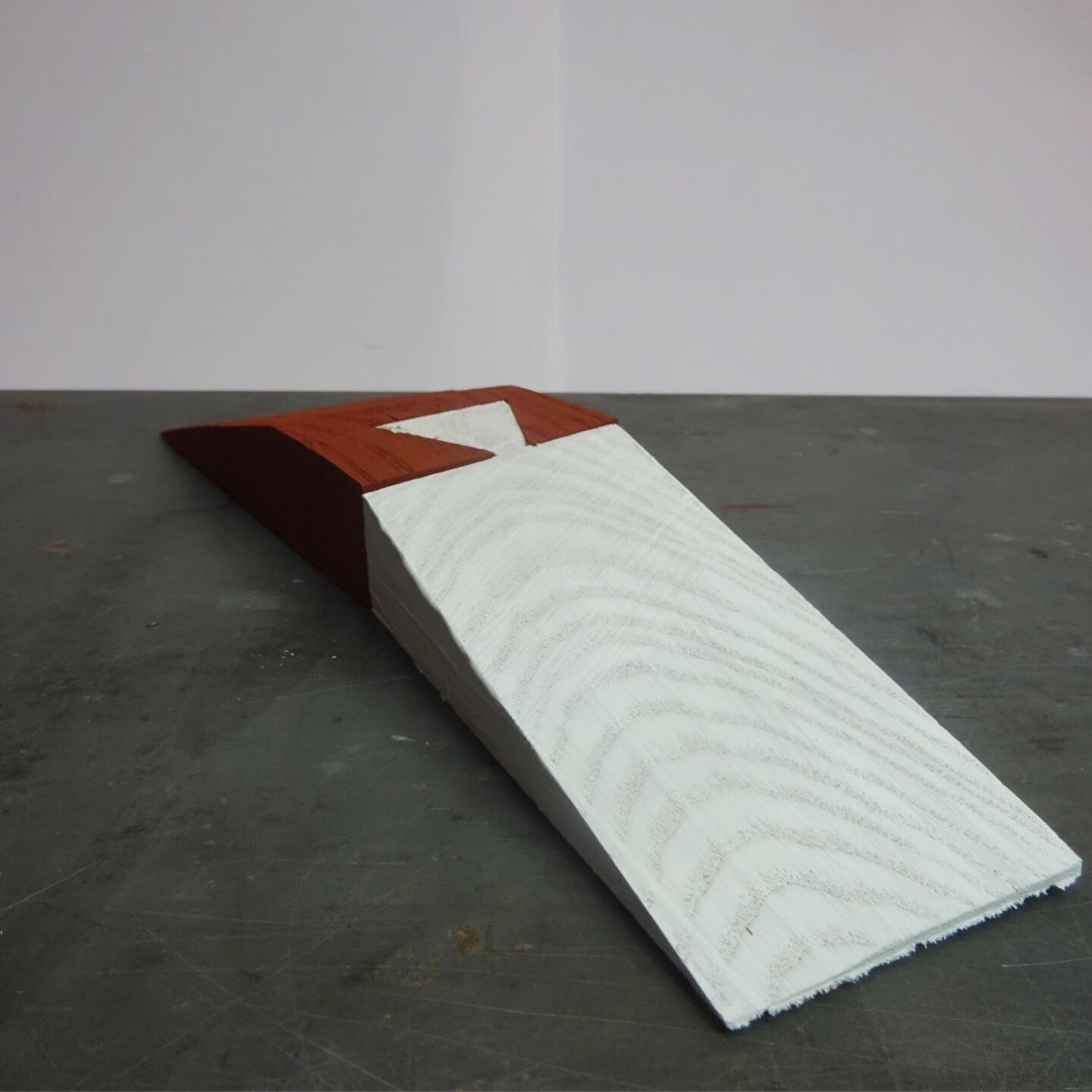 Two wedges dovetailed with a single crude Dovetail, one is painted red, the other, White.