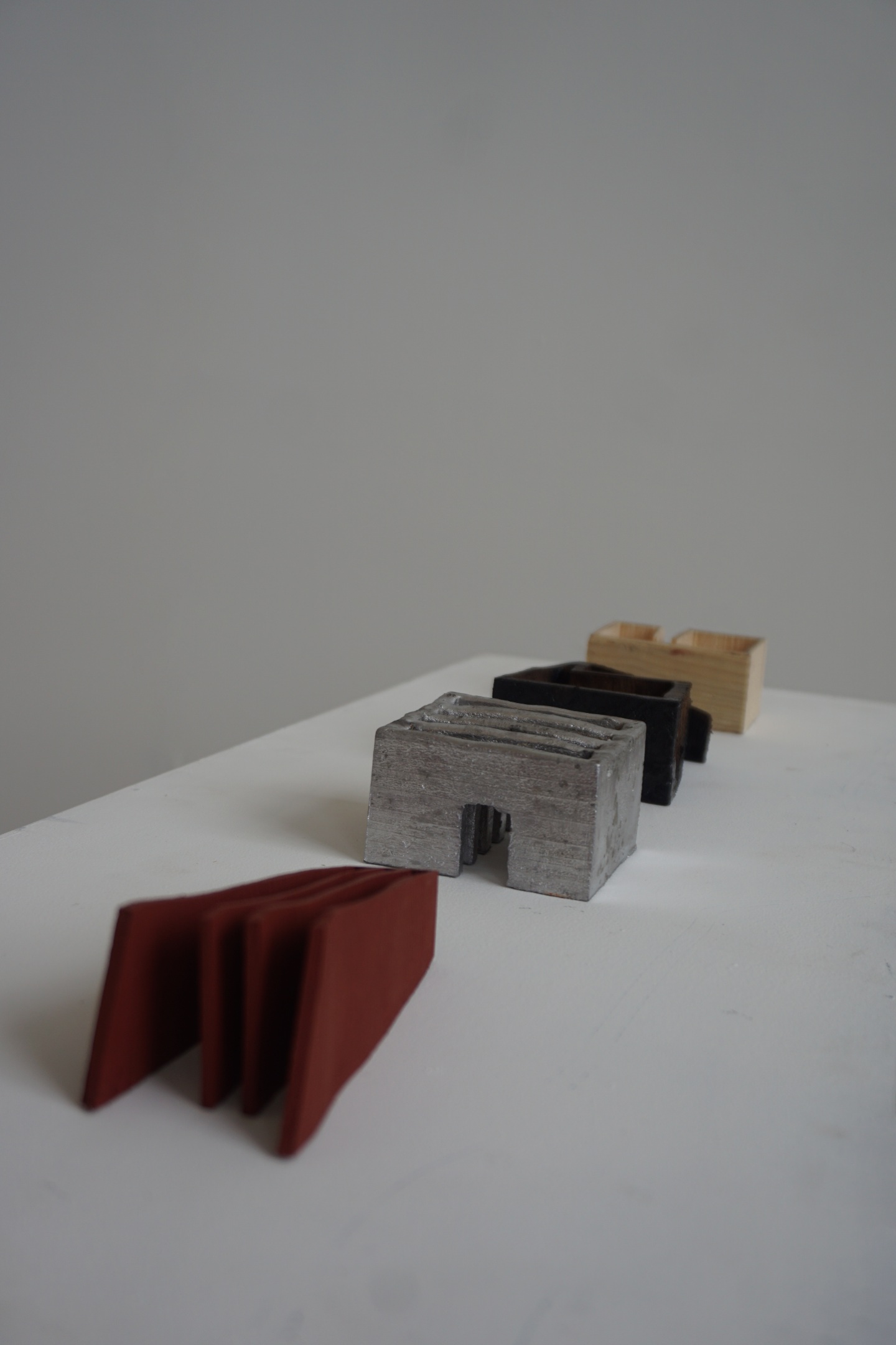 A row of small architectural sculptures, lined up as if heading somewhere. 