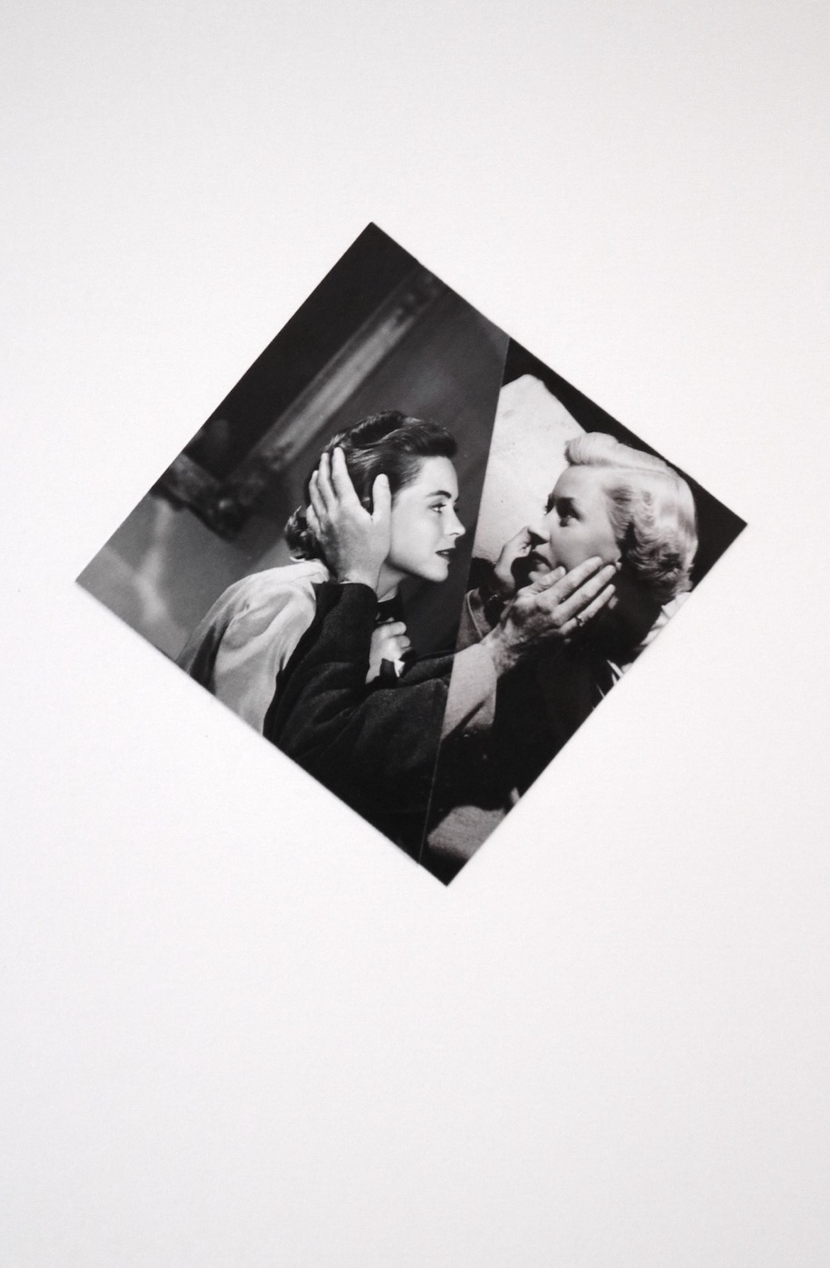 a black and white diamond shaped collage. two women embrace at the cheek, a single cut fusing them.