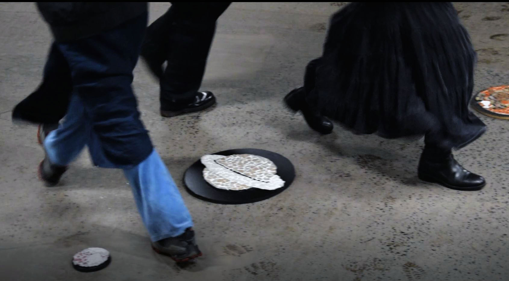 Park Space Ritual; image depicting the legs of three people circumambulating a mosaic of Saturn on granite flooring