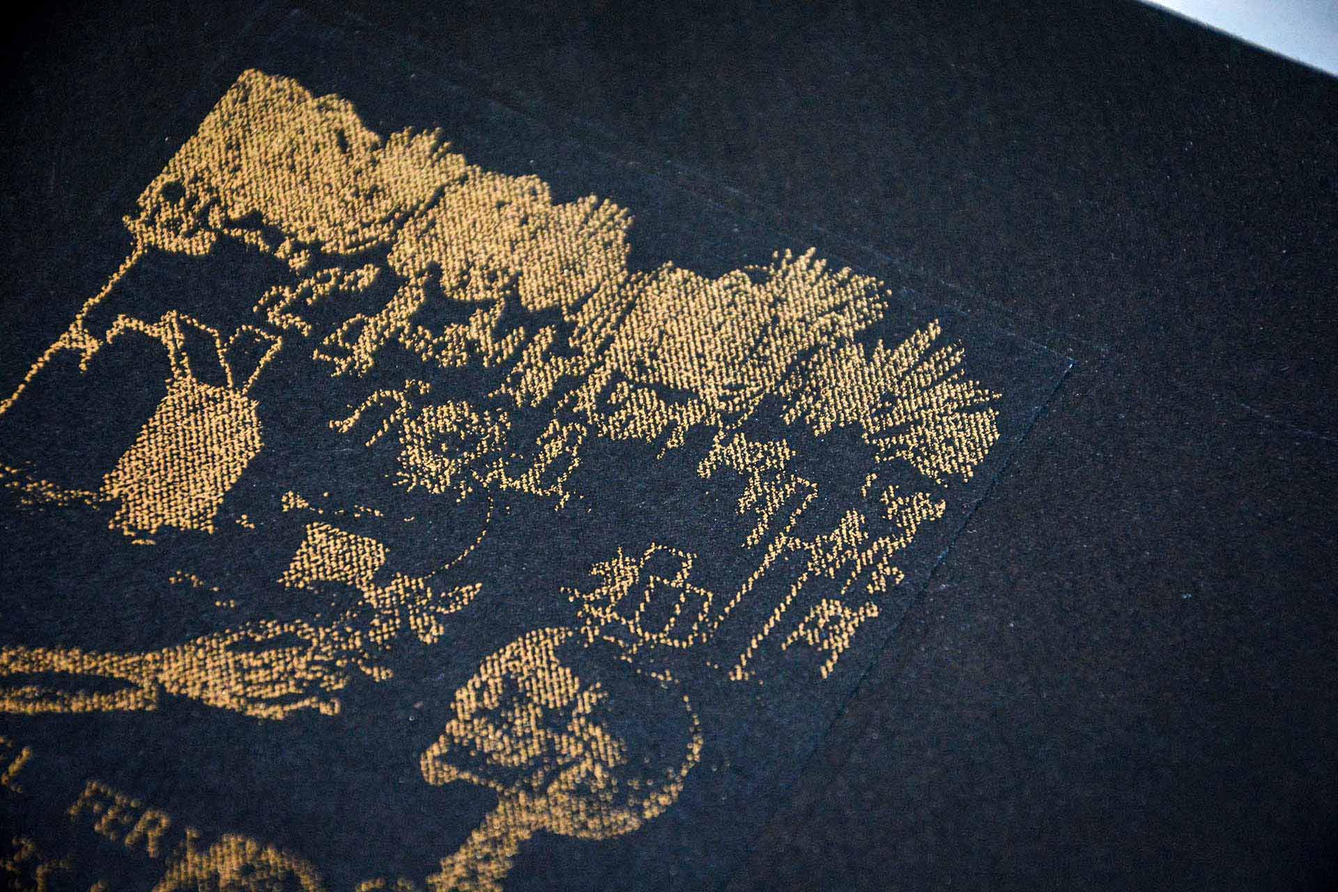 Close up of the gold foil artwork on the front cover. Skeleton skull and drawing of graveyard visible.