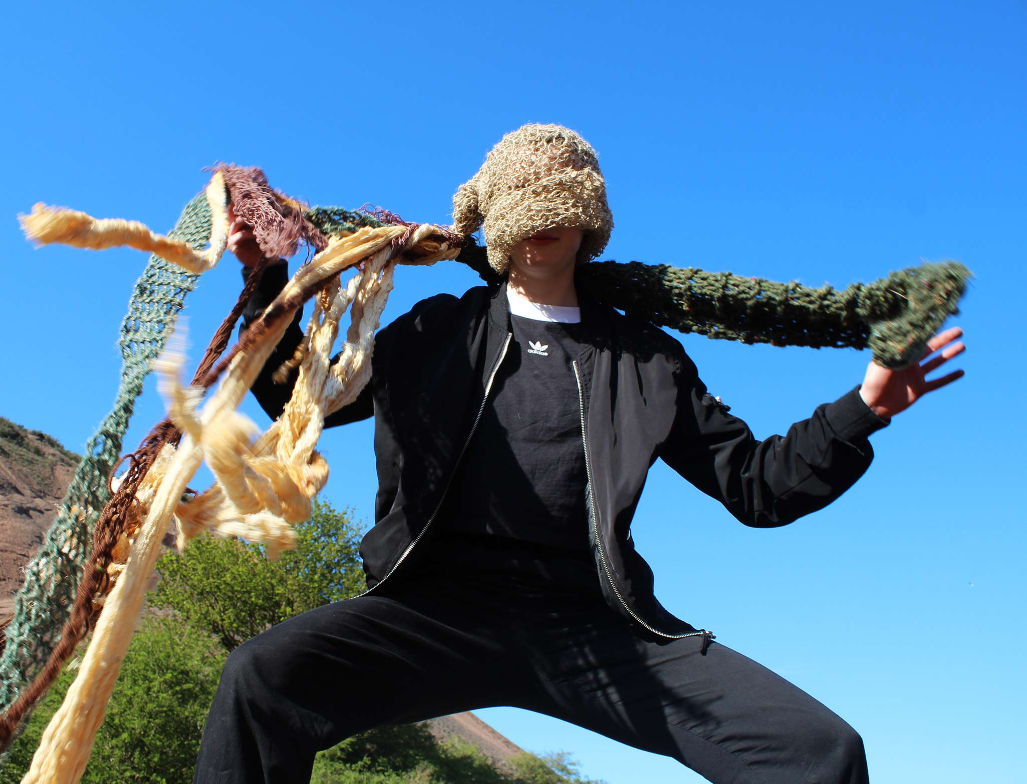 Person wearing knitted hat with tendrils with a blue sky background 