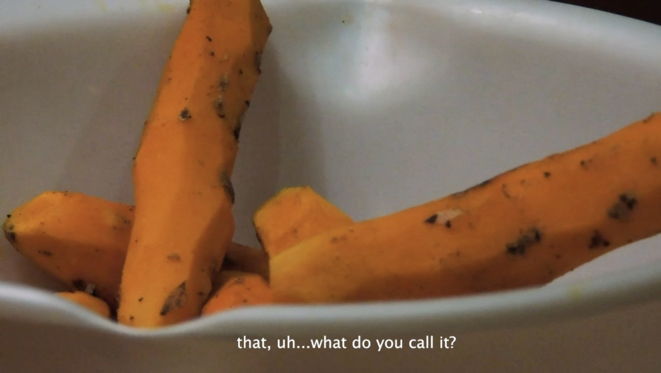 Video still of 'Visual Recipe' with translated subtitles, close-up of peeled turmeric roots.