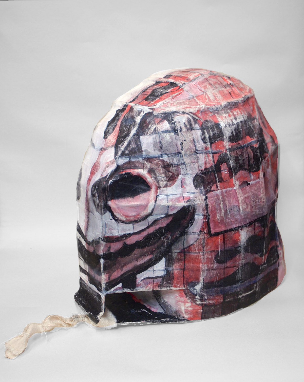 Photo of a papier mâché helmet with eyes and a big smile painted on it (left side)