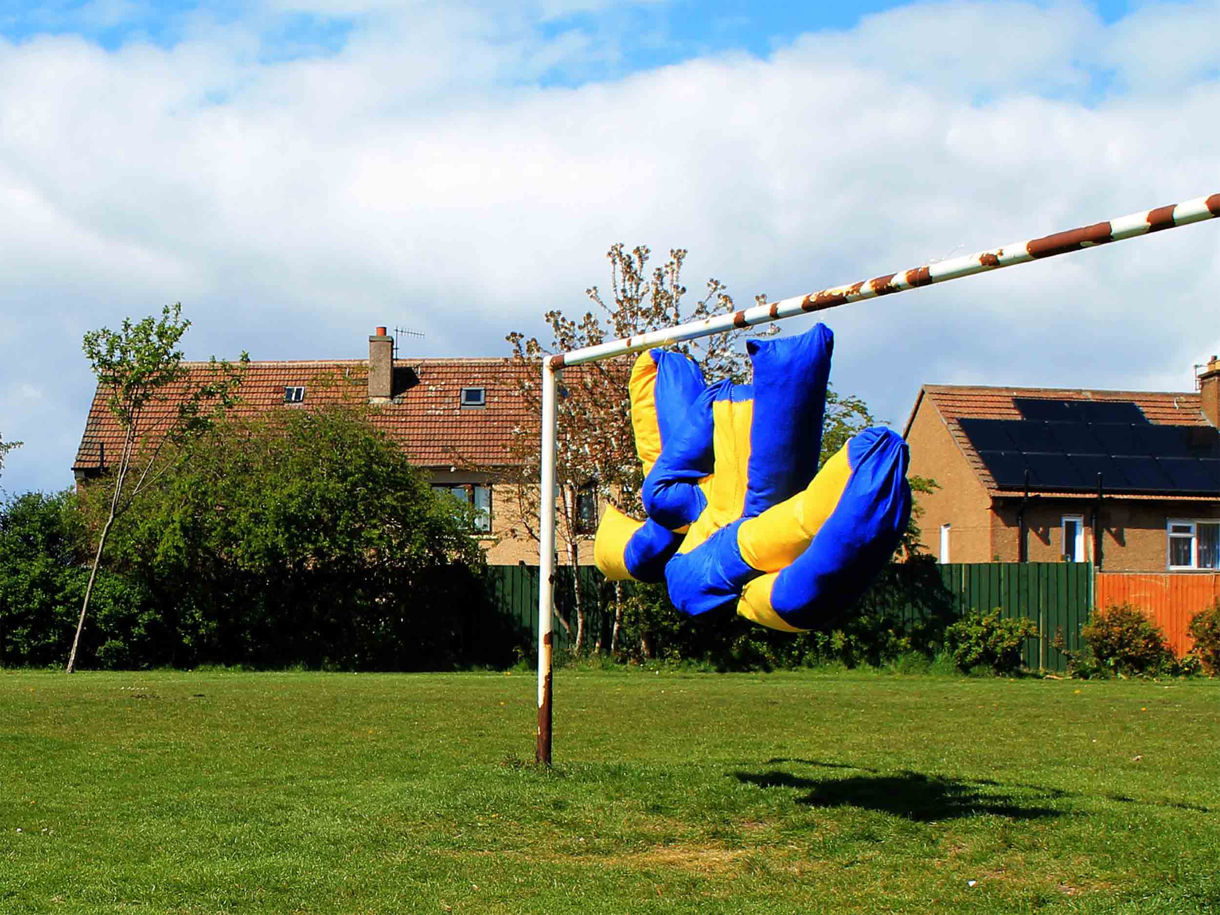 Blue and Yellow soft sculpture suspended from white goal post. 