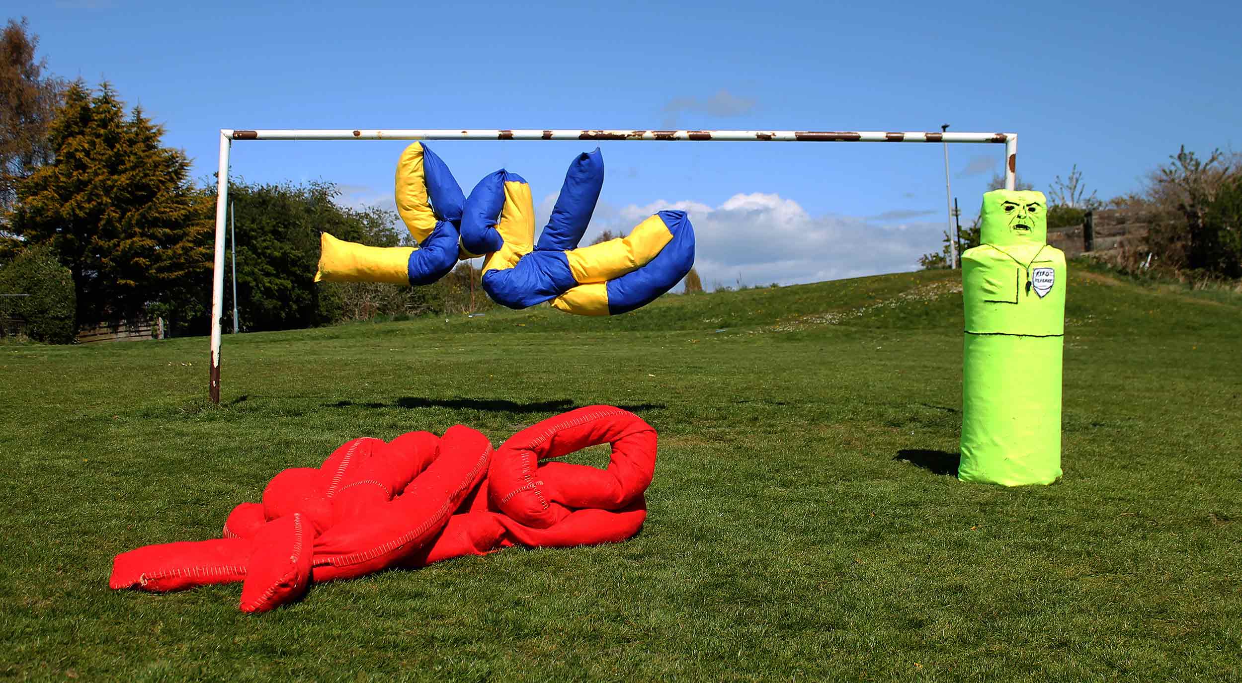 Three soft sculptures displayed near a white goal post.