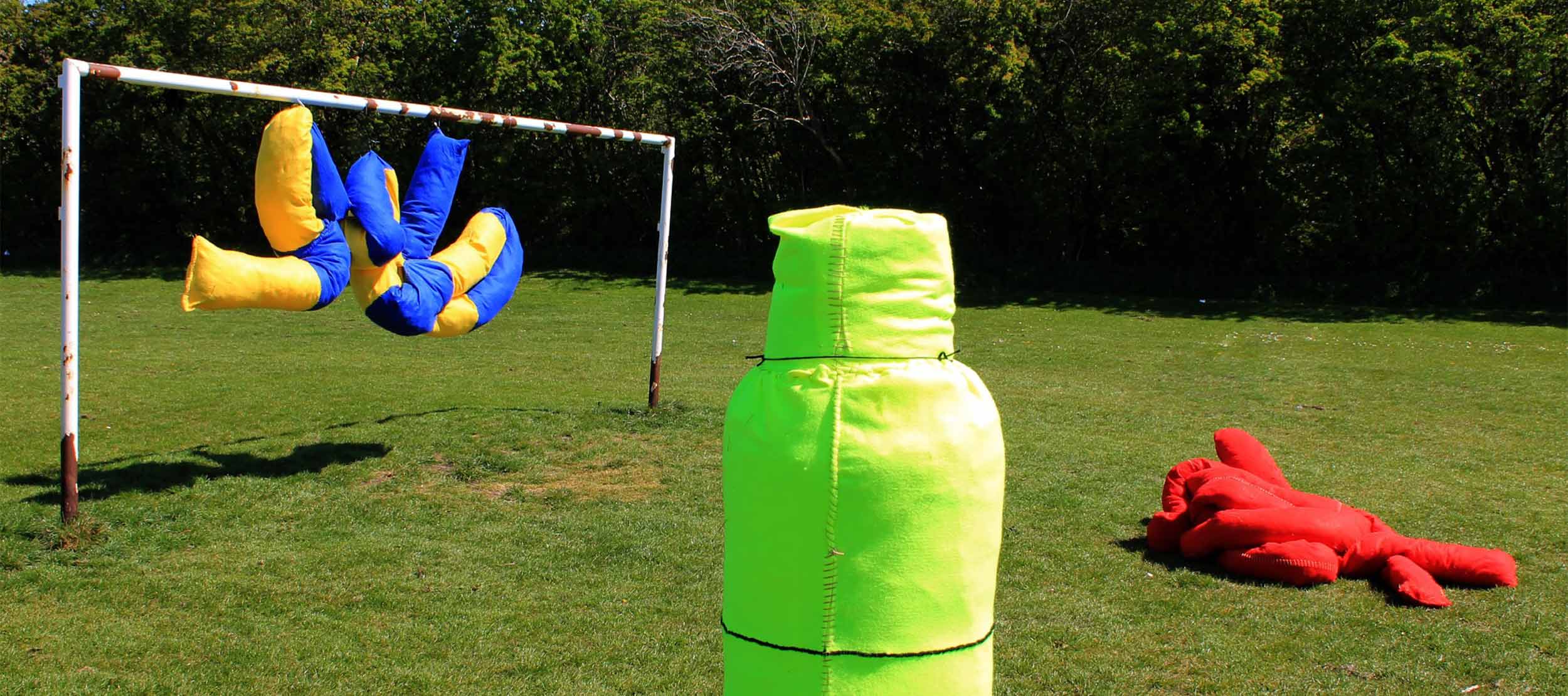 Three soft sculptures displayed near a goal post