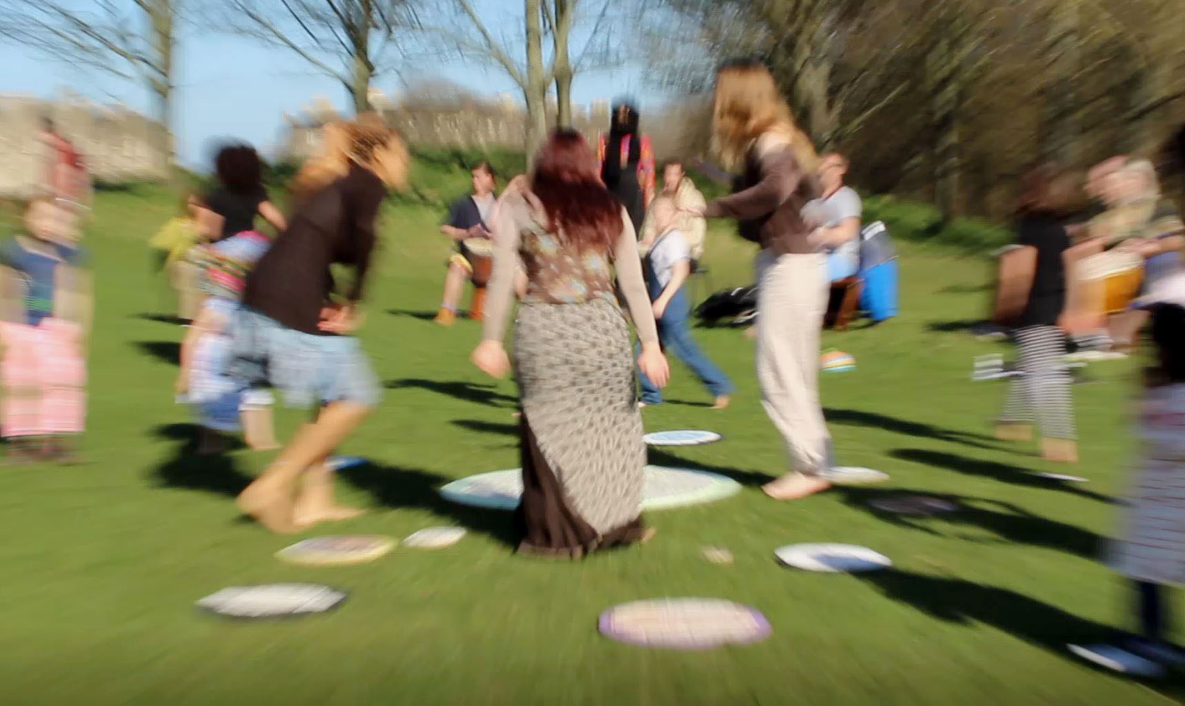 Distorted and blurred image of people doing a ritualised dance around the solar system