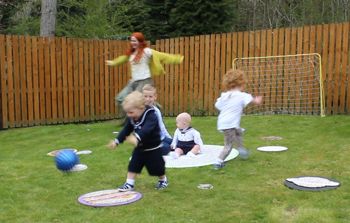 Artist and children engaging in a domestic garden setting with the mosaics of the solar system