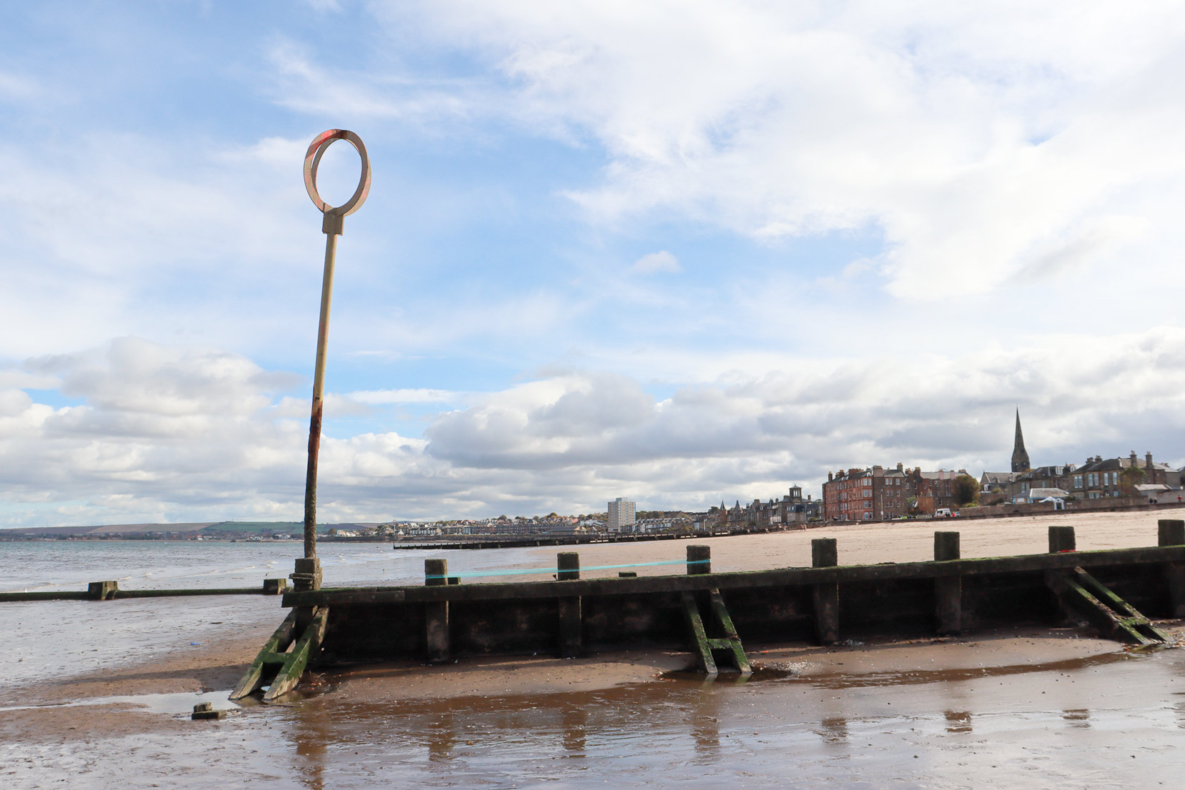 Strands of blue yarn wound around three groynes on a beach. 