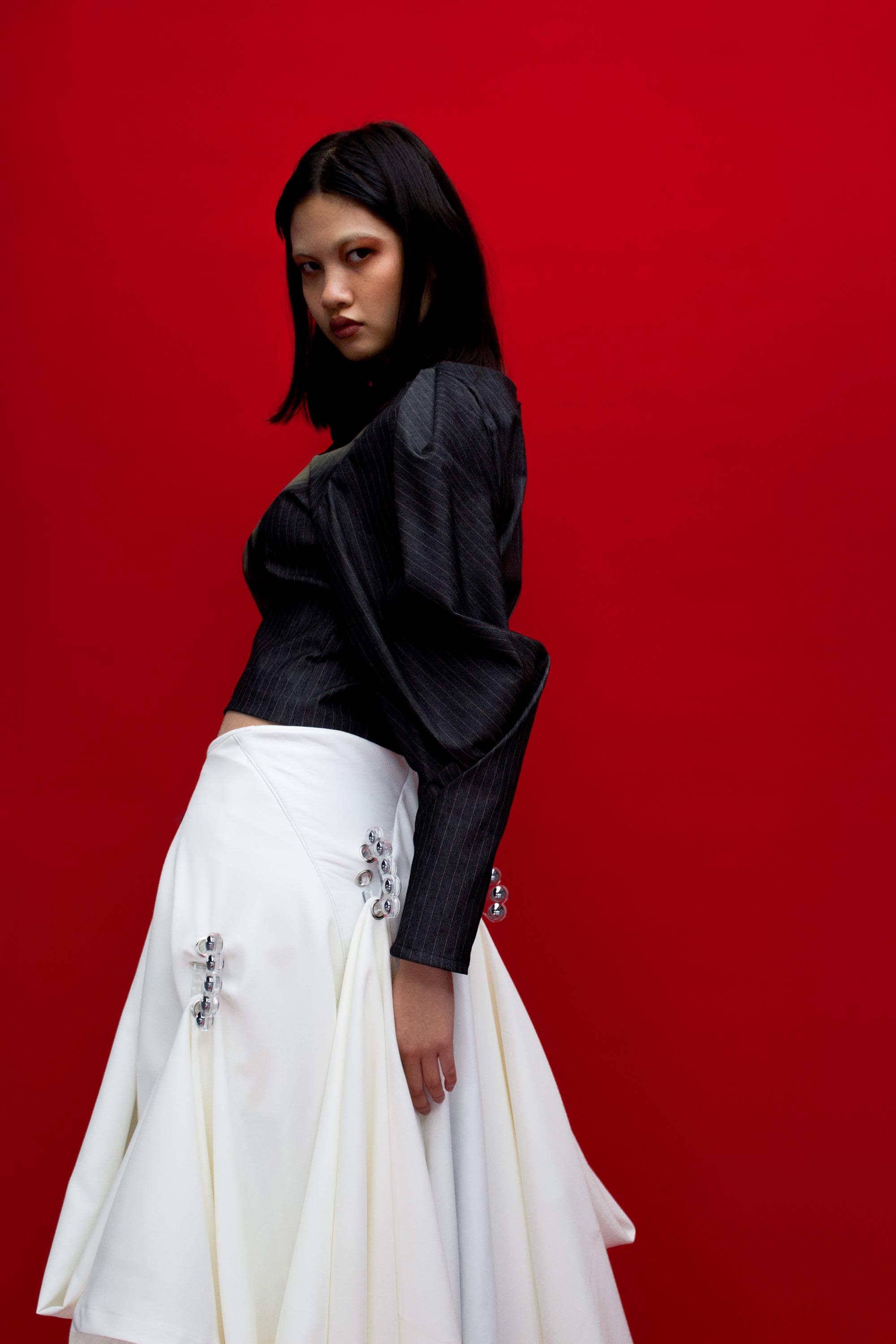 Model wears pinstripe top and draped skirt