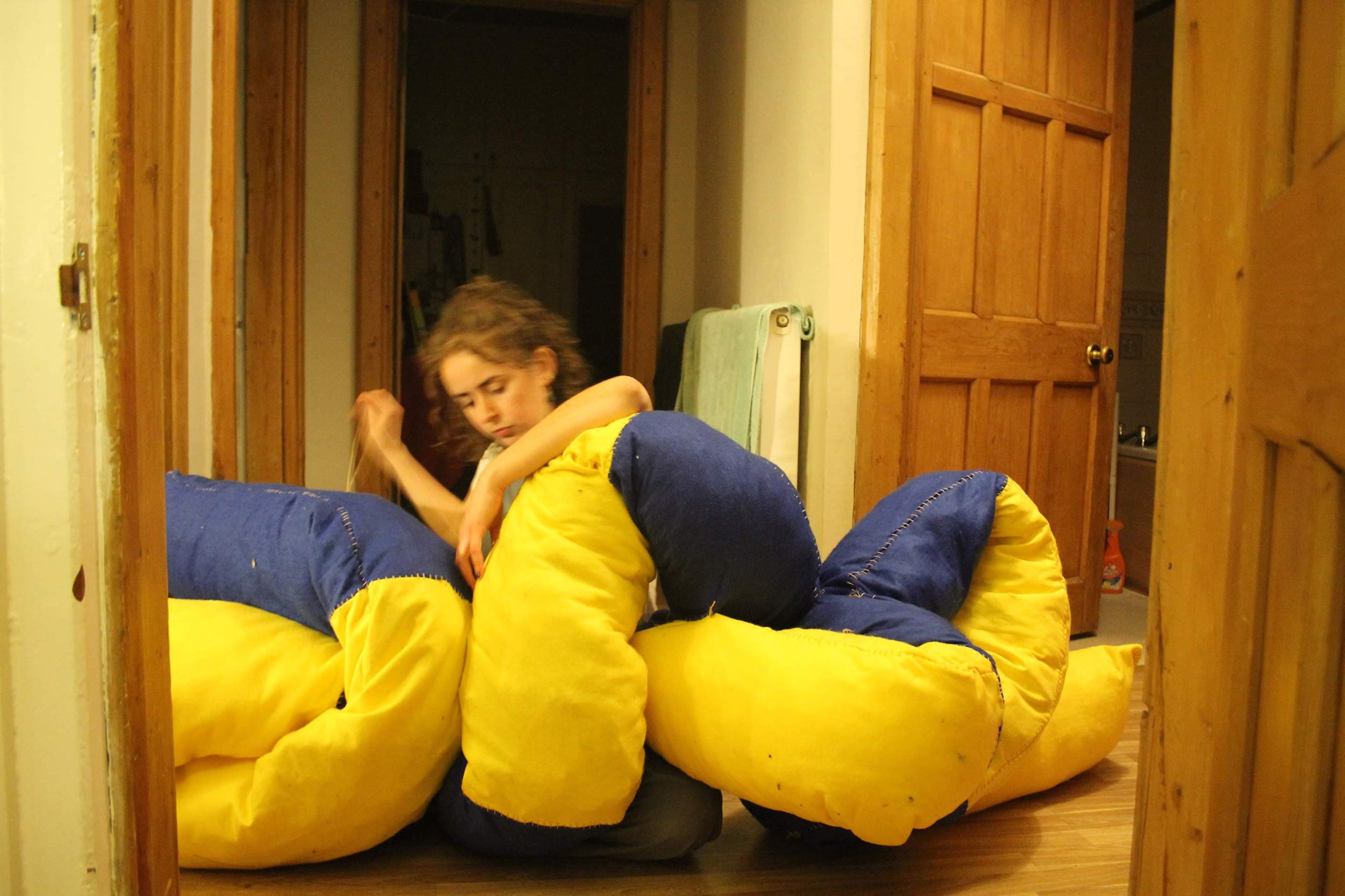 Image of Charlotte sewing blue and yellow sculpture. 