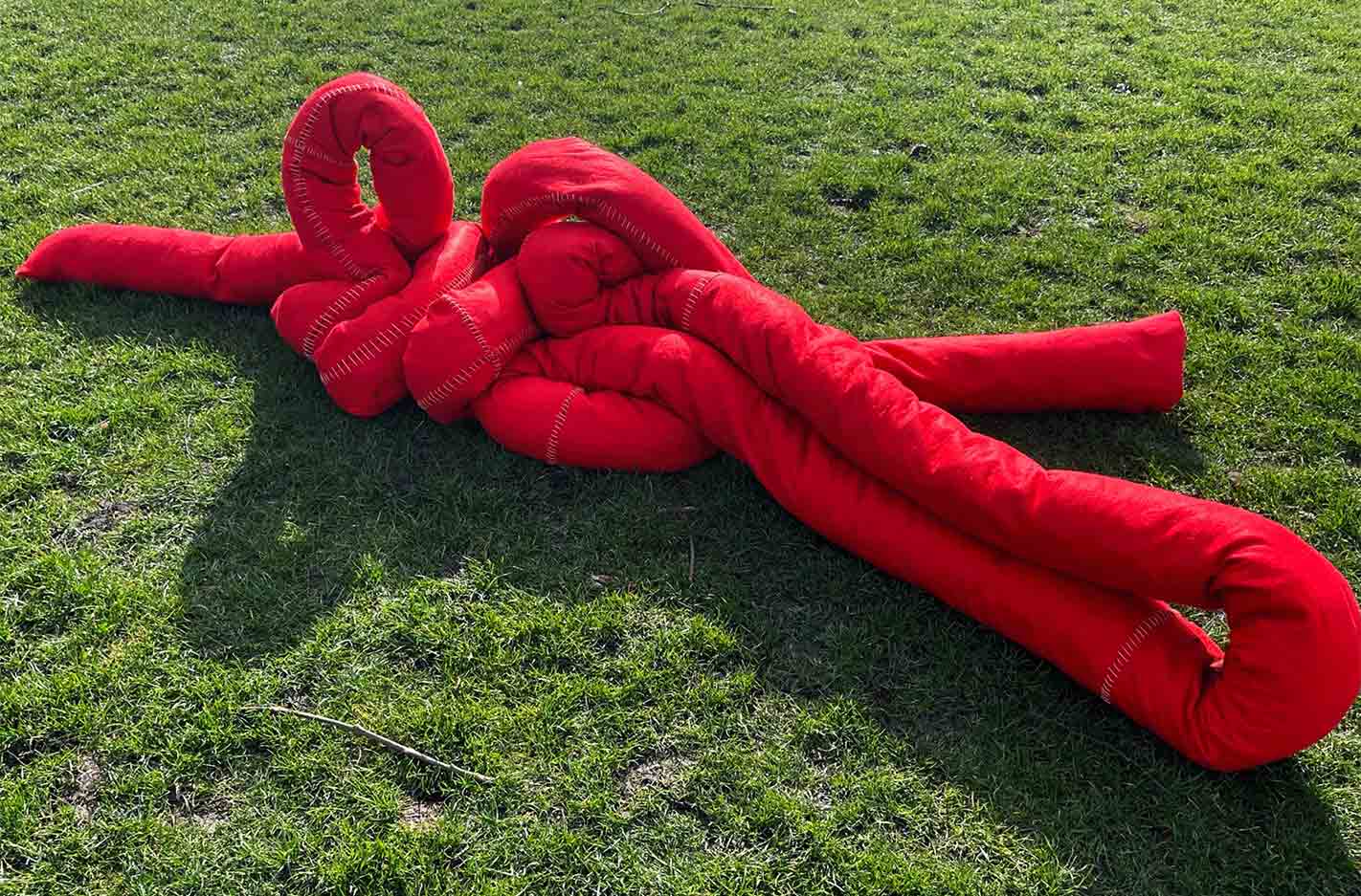 Red soft sculpture situated on grass. 