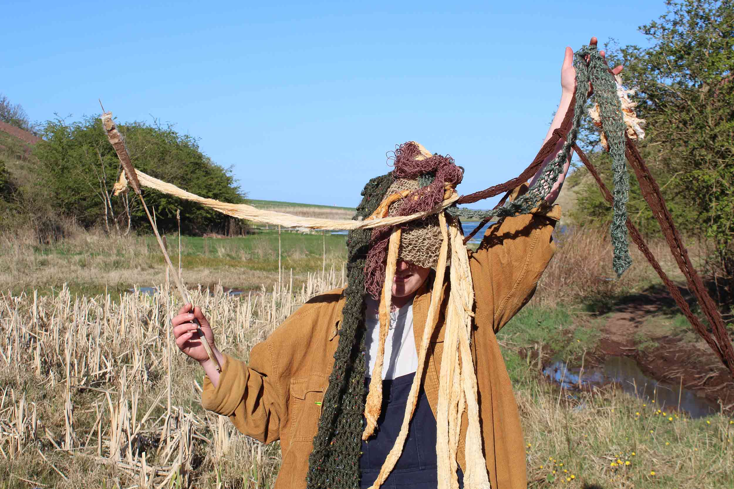 Person wearing knitted tendrils from wool, twine and scrim