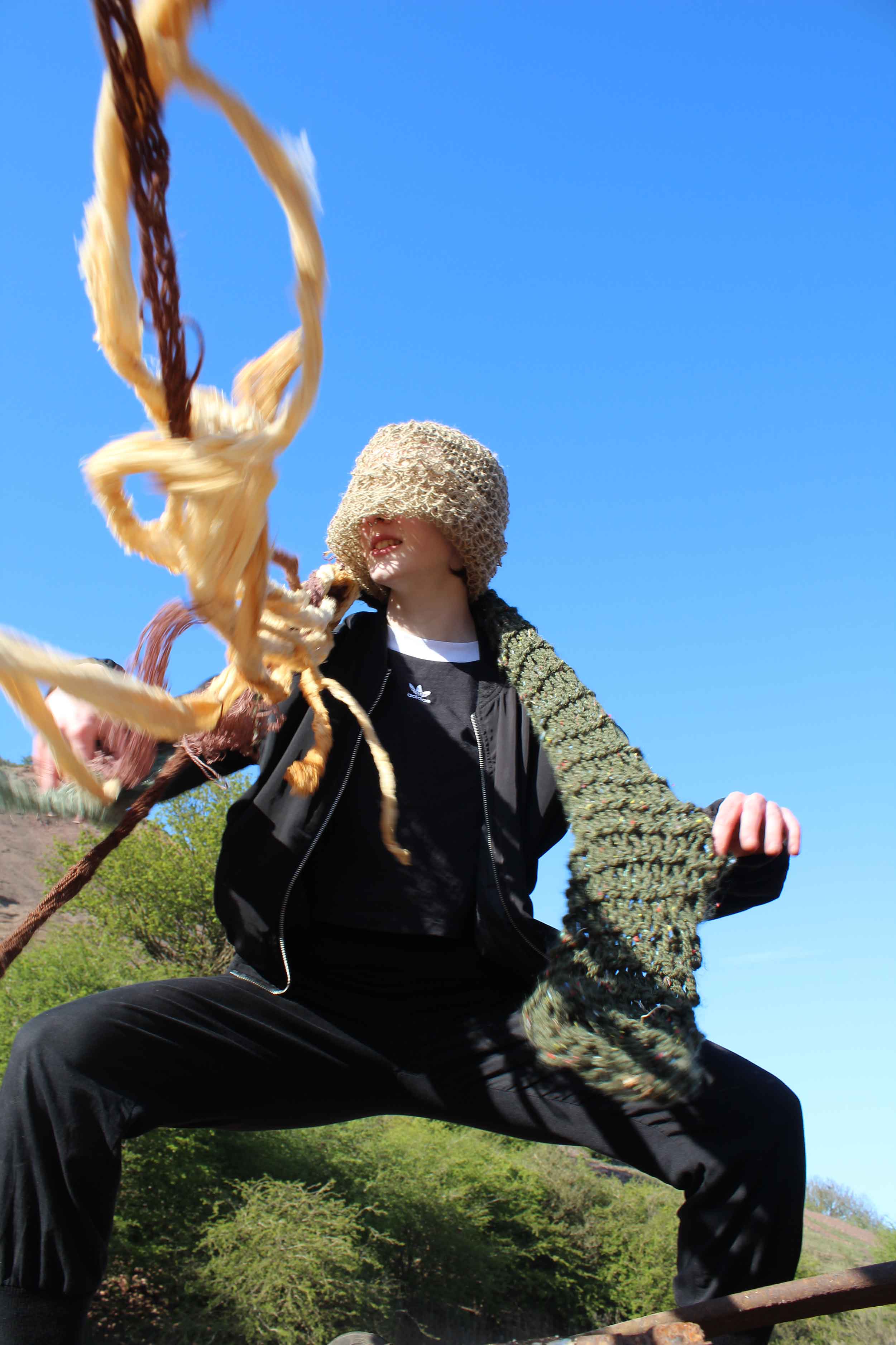 Person wearing knitted hat with tendrils with a blue sky background 