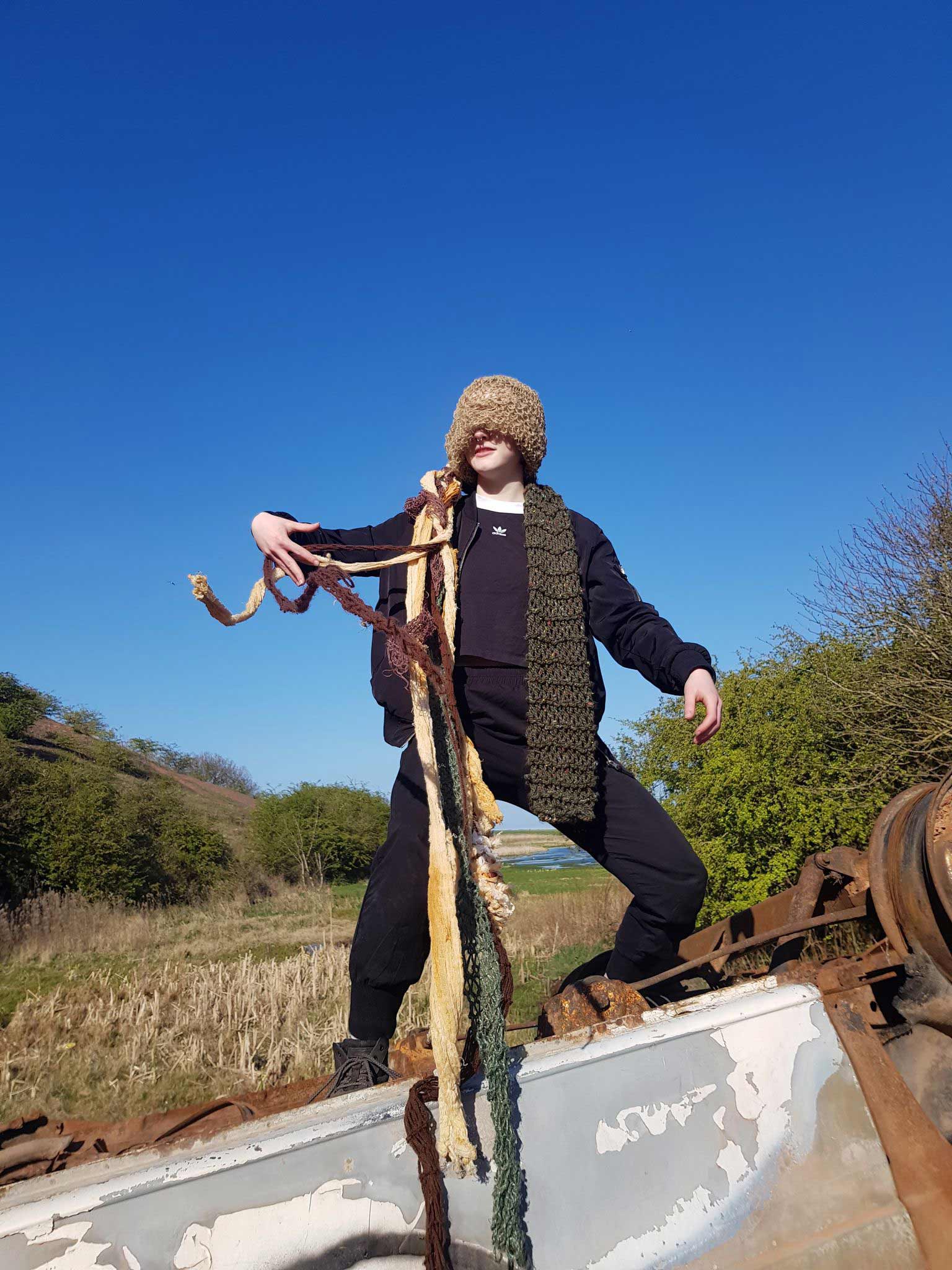 Person wearing knitted hat with tendrils with a blue sky background 