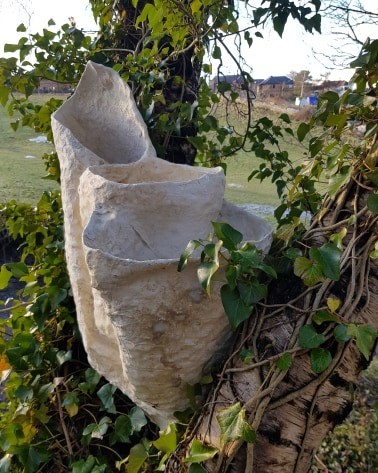Tulip shaped sculpture nestled into a tree with ivy surrounding it. 