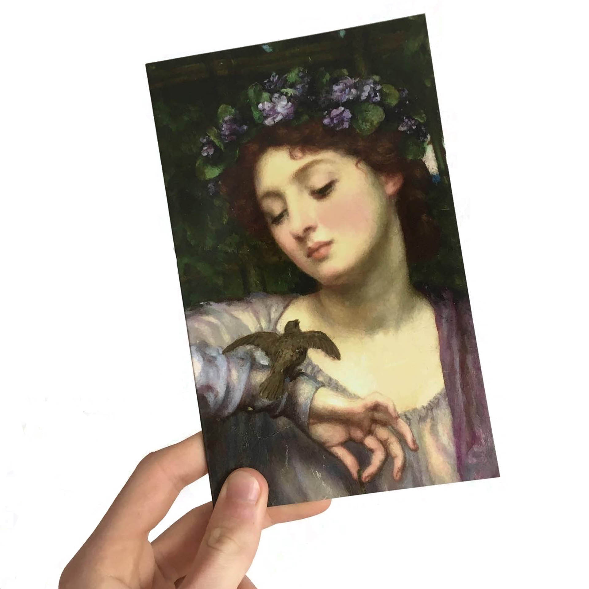 A booklet being held by a hand. The cover shows a painting of a woman looking at a bird resting on her wrist.