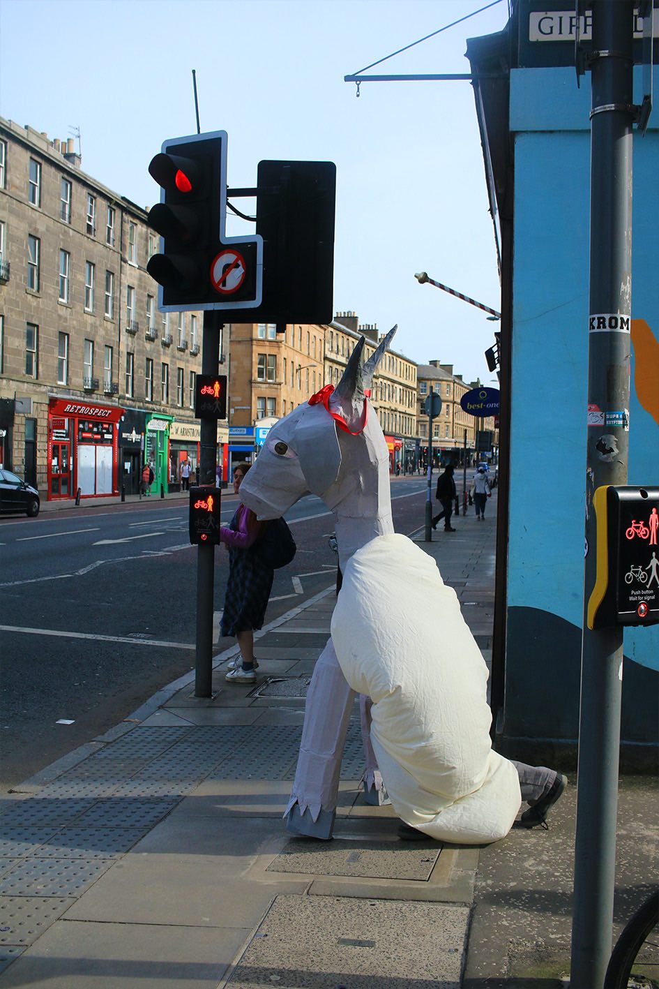 Figure in a papier-mache goat costume stood at traffic lights.
