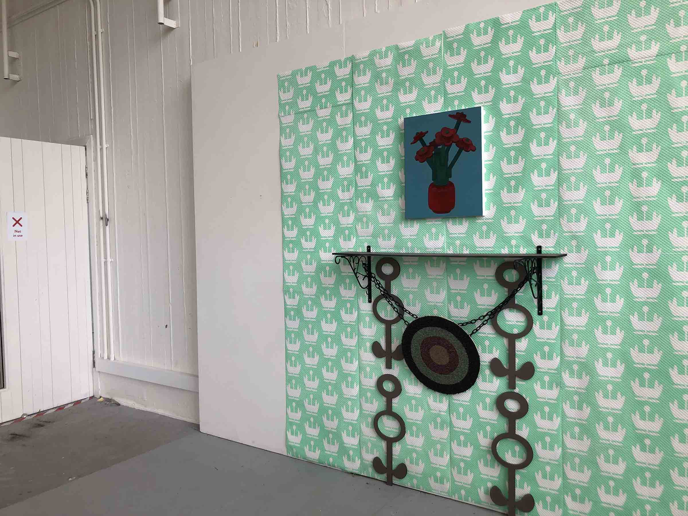 pastel green wallpaper, MDF mantelpiece, carpet target, lego flowers painting 