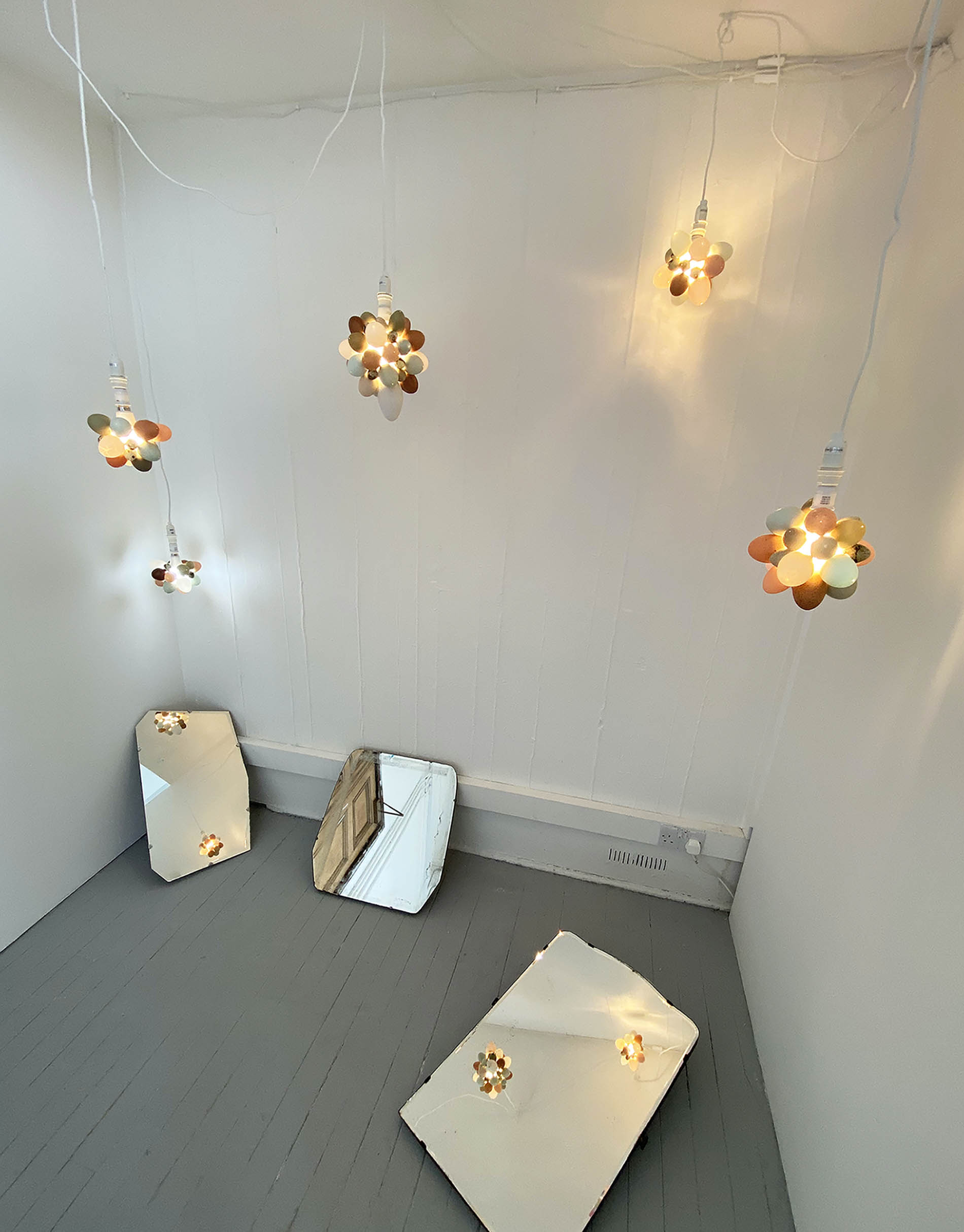 Wide view of illuminated eggs install reflected in 3 antique mirrors