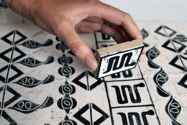 Hand holding a stamp printing onto natural fabric