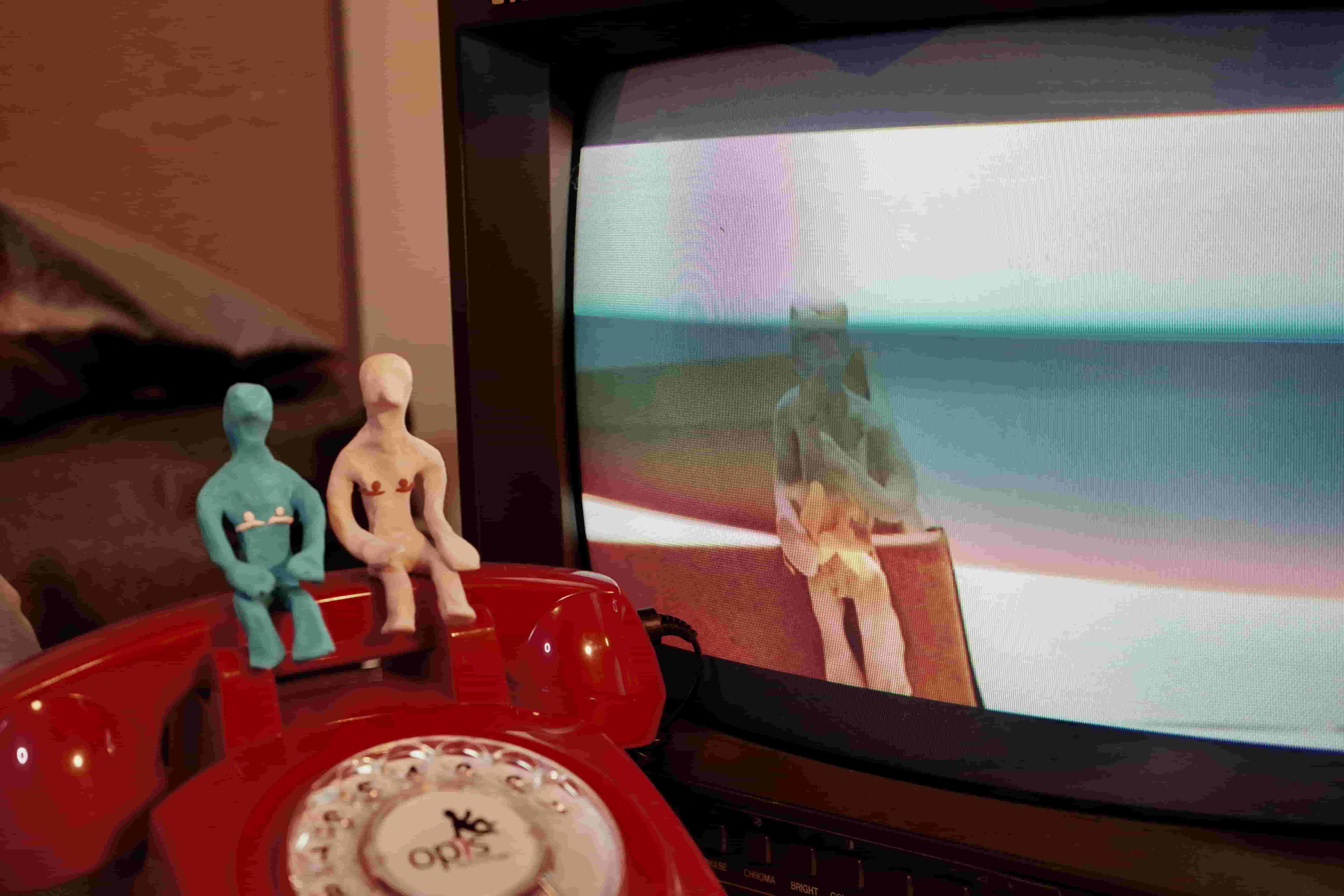 2 plasticine figures sitting on telephone