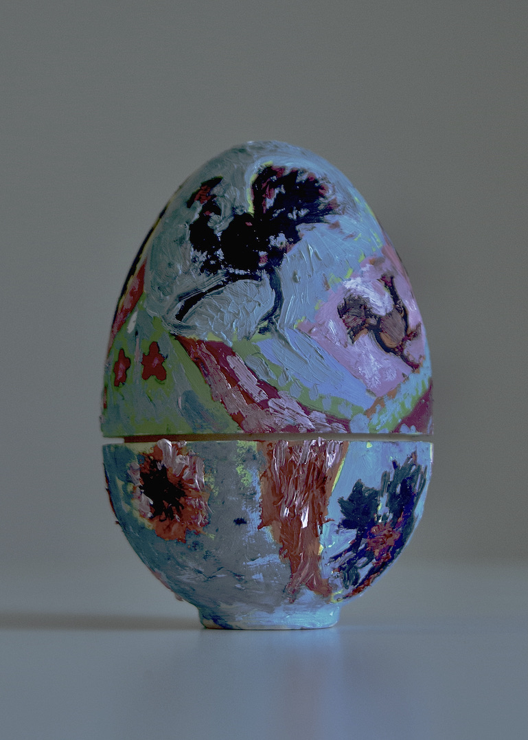 Colourful painted wooden nesting egg with images of birds and flowers on the surface.