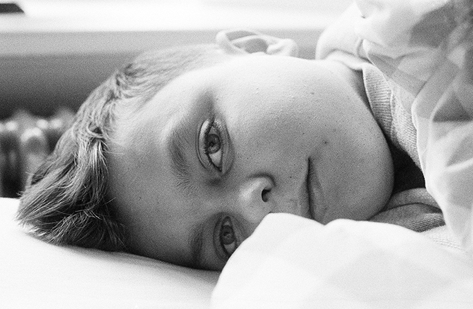 Portrait of a young boy lying on his side in black and white