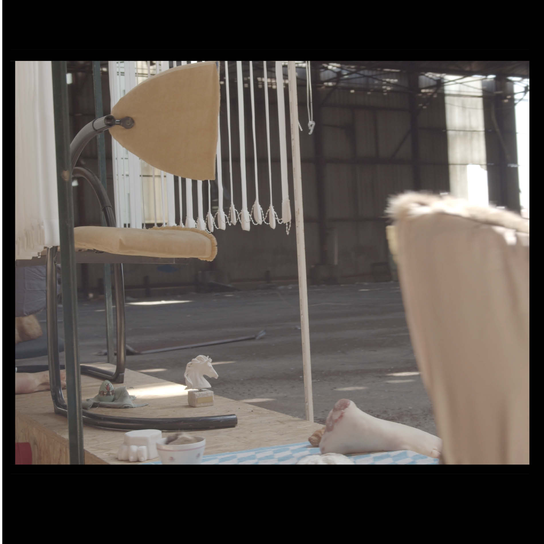 L'usine MF. Still of a filmed scenography, France, April 2021. Whipped cream, snake boot, horse statue, vertical blinds, pork trotter, tennis towel.