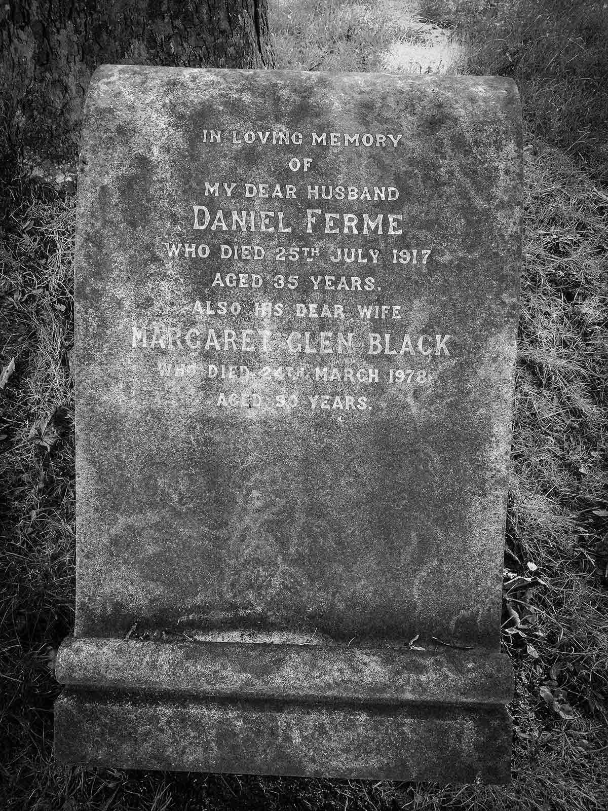 Greyscale image of a regtangular headstone displaying the text "In Loving Memory of my dear husband Daniel Ferme who died 25th July 1917 aged 35 years. Also his dear wife Margaret Glen Black who doed 24th March 1978 aged 90 years."