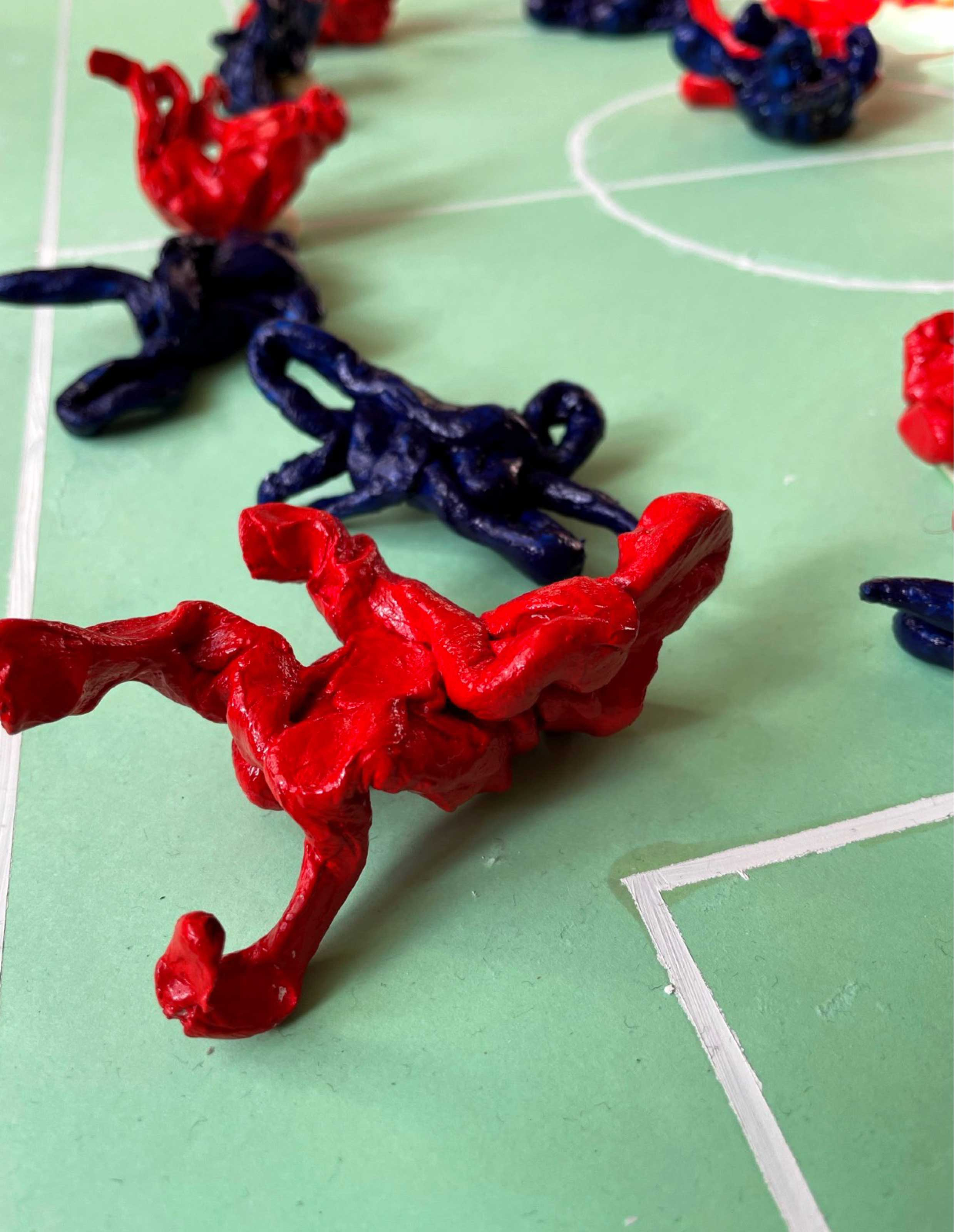 Detail image of small blue and red figures on model football pitch. 