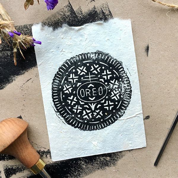 A lino printed design of an Oreo biscuit. Printed in black ink on white paper. 