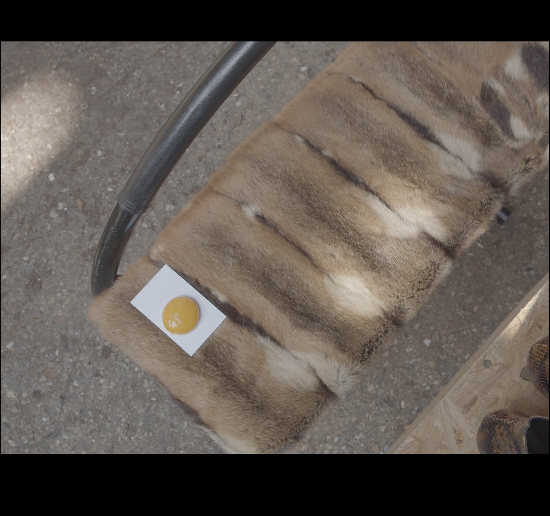 L'usine MF. Still of a filmed scenography, France, April 2021. Egg yolk, waiting room chair cut in half, fur.