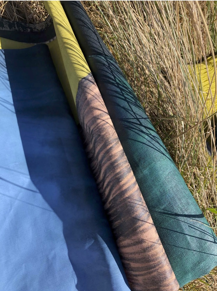 Three textiles samples laid across each other, blending into the natures textiles, creating shadows.