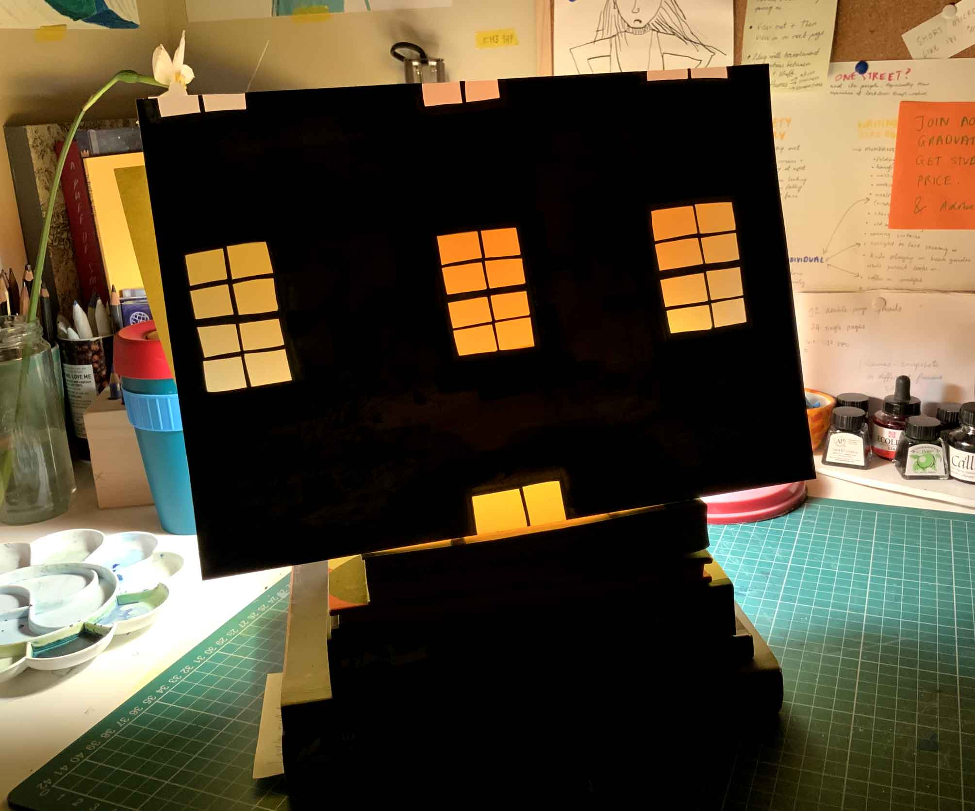 A cut out of a window. The light from the window is orange against a black background.