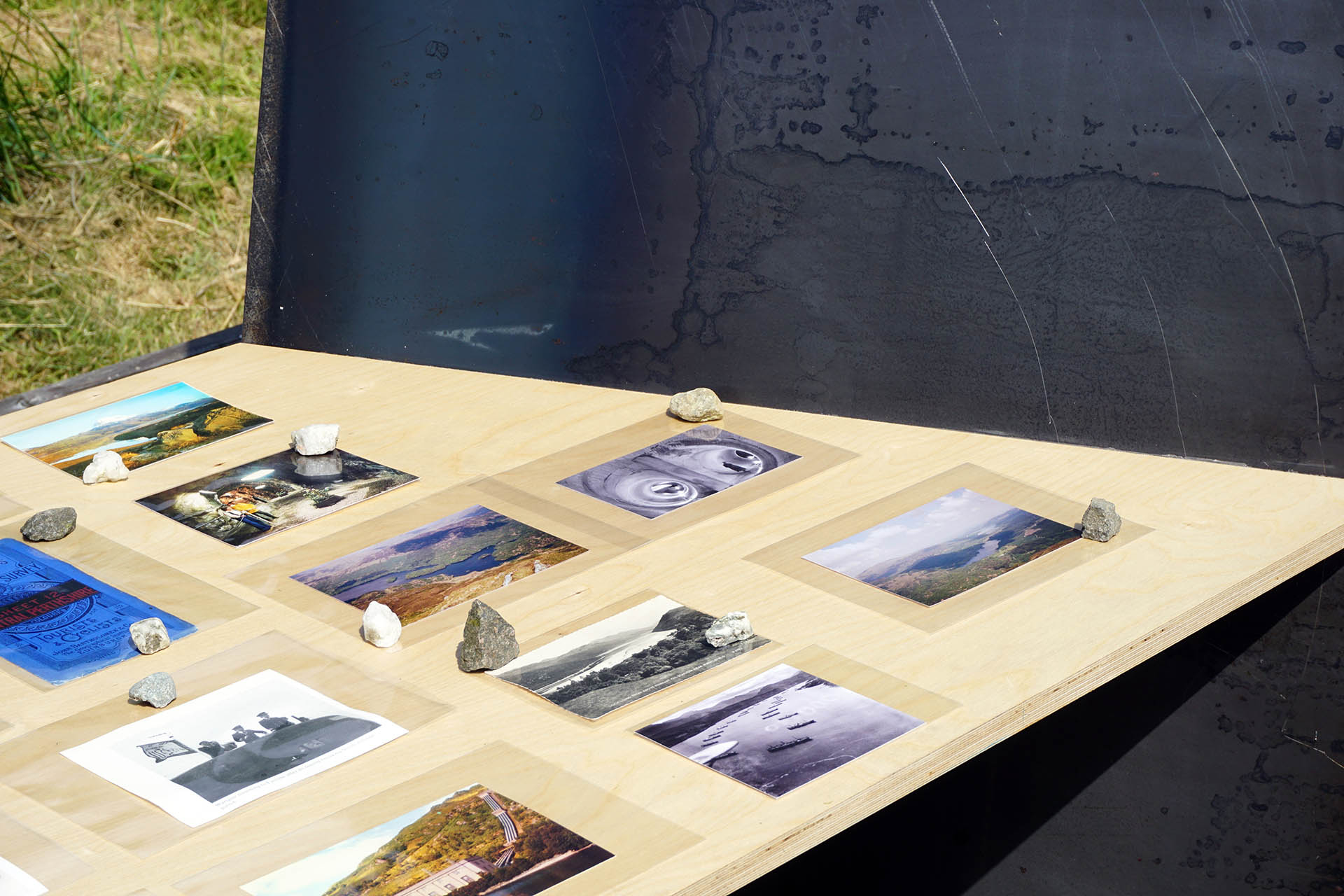 Collected archival materials displayed on birch ply table with hot rolled steel acoustic deflector sliced through it, set at an angel 