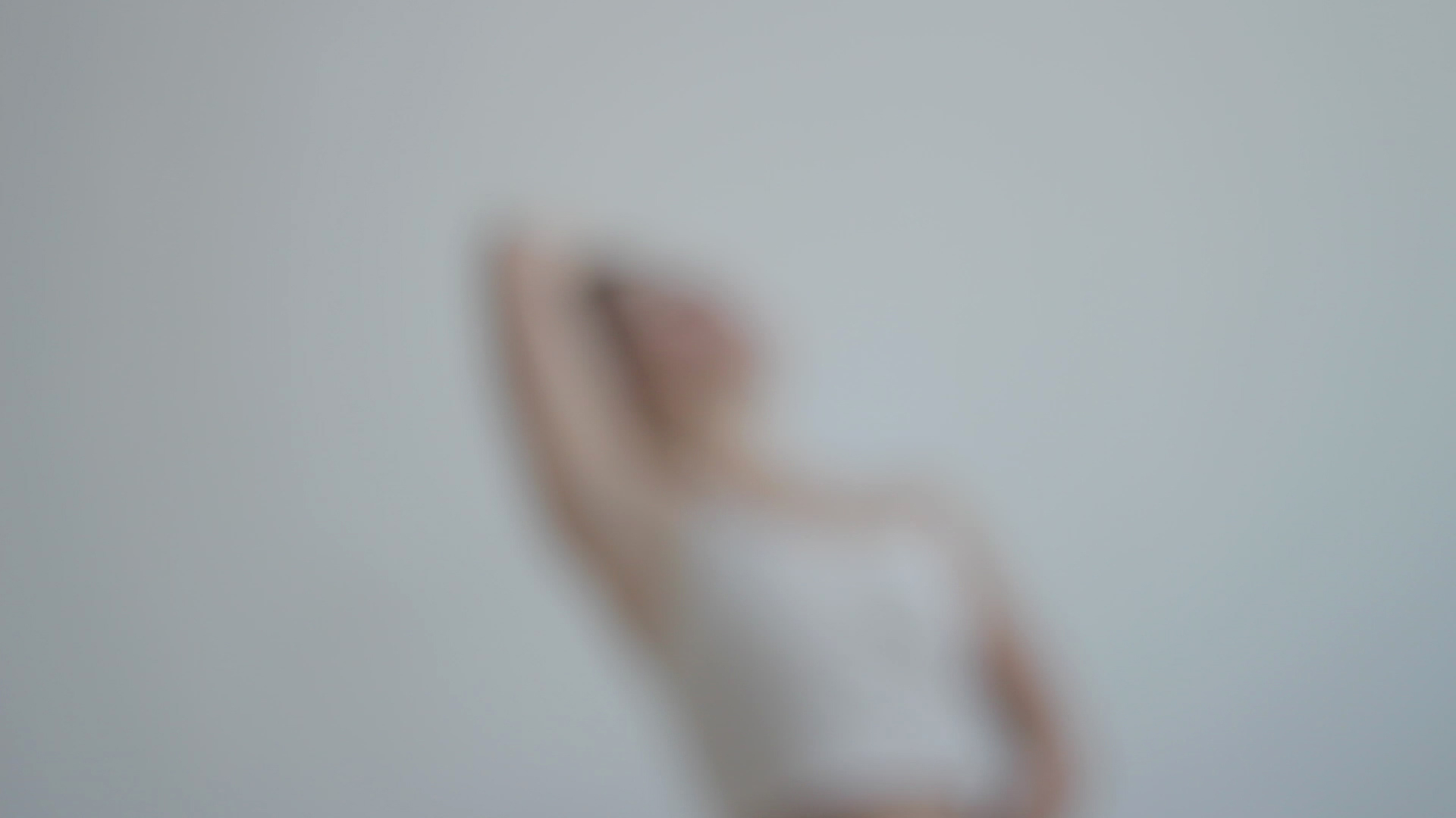 The blurred figure of a dancer wearing a white shirt in a white background.