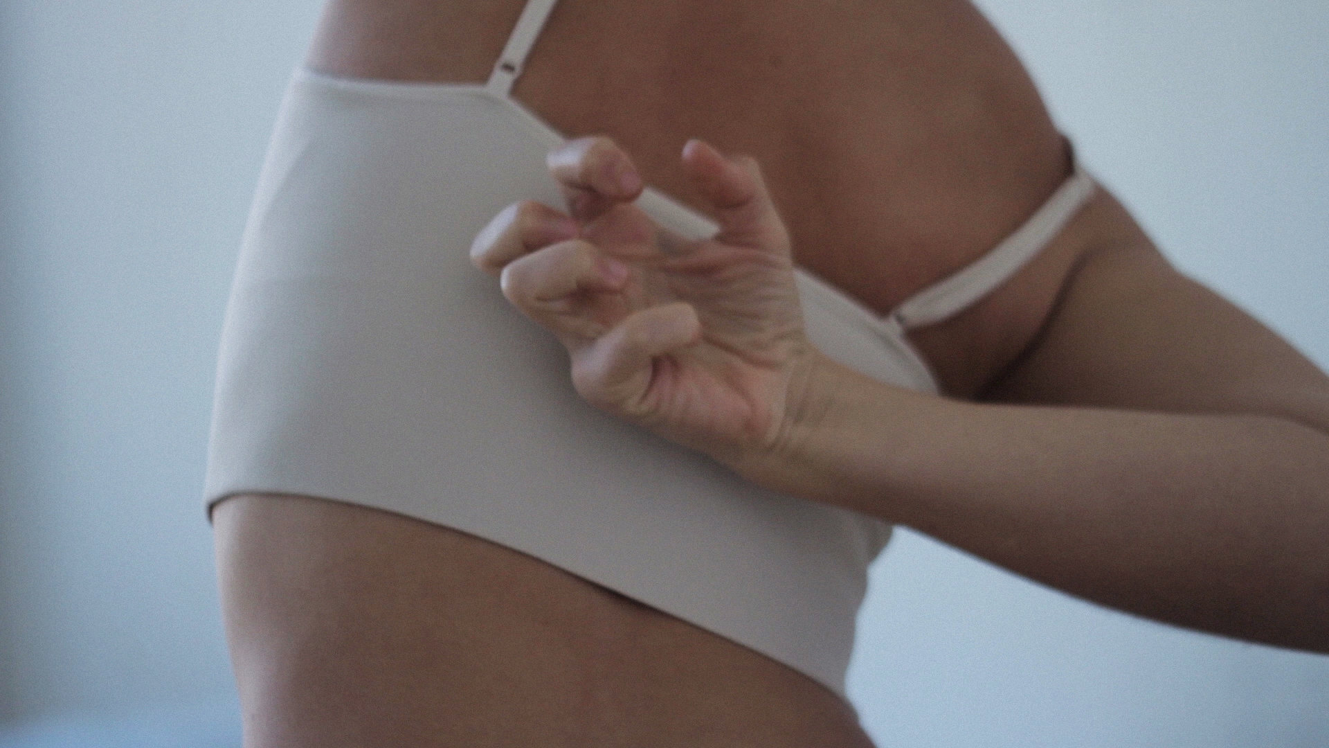 A medium shot of a dancer, with her hand tensed on her back.