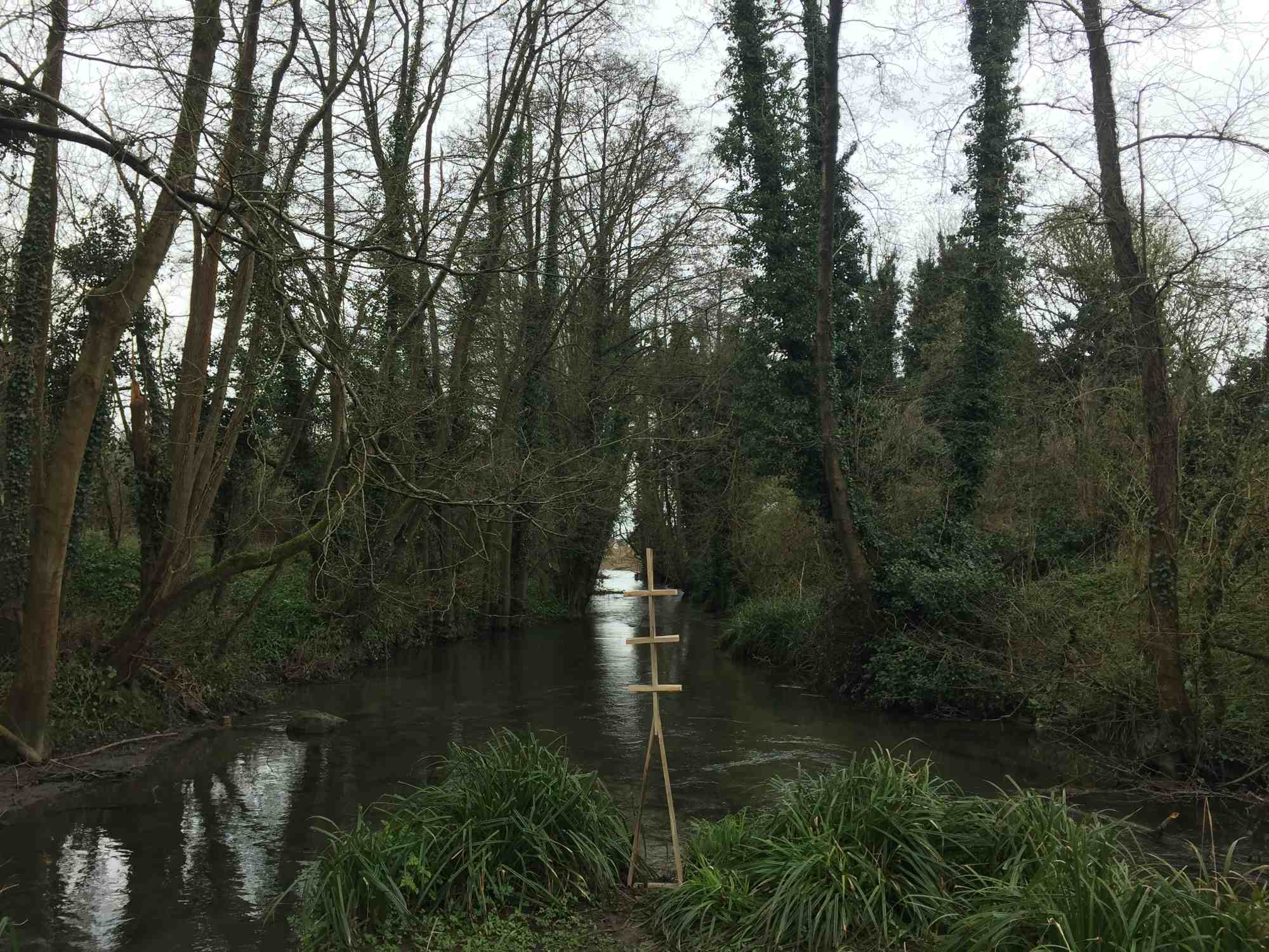 A wooden sculpture stood on the bank of two converging rivers.