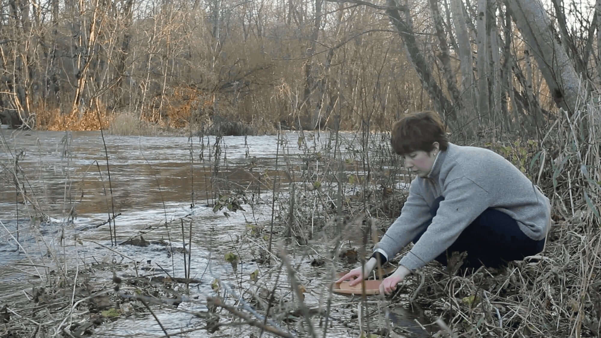 The artist placing a terracotta vessel into the Kunda River.
