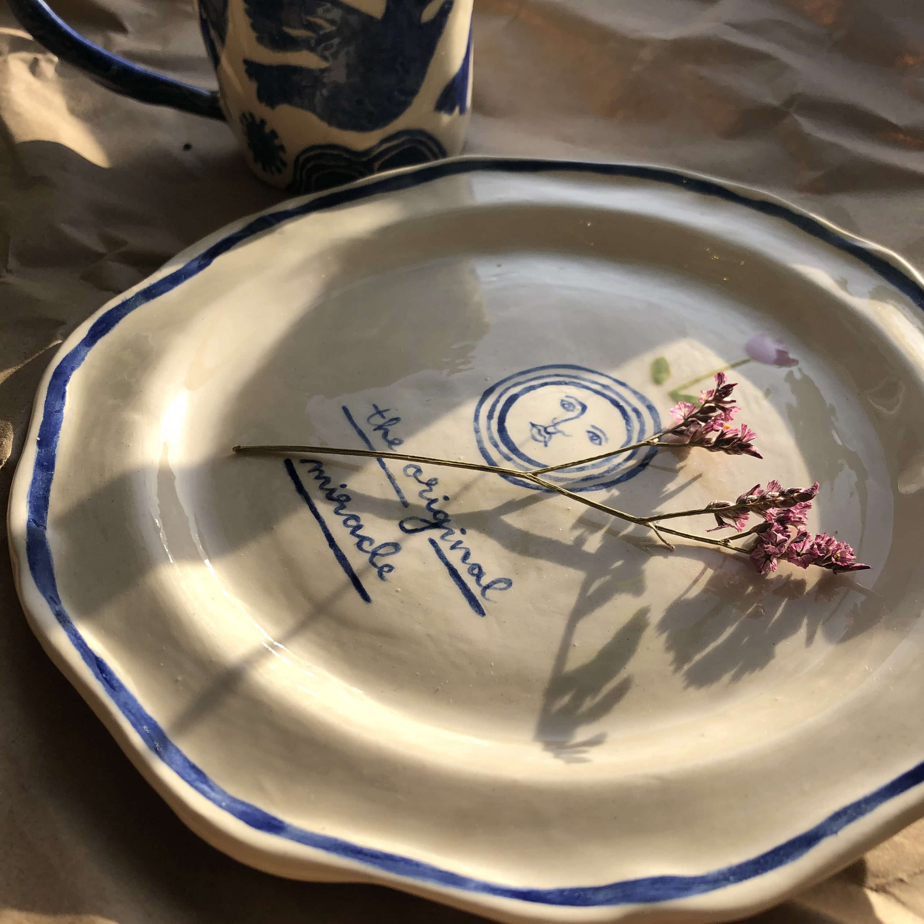 Handmade ceramic plate with a sun motif in the centre with the words 'the original miracle'