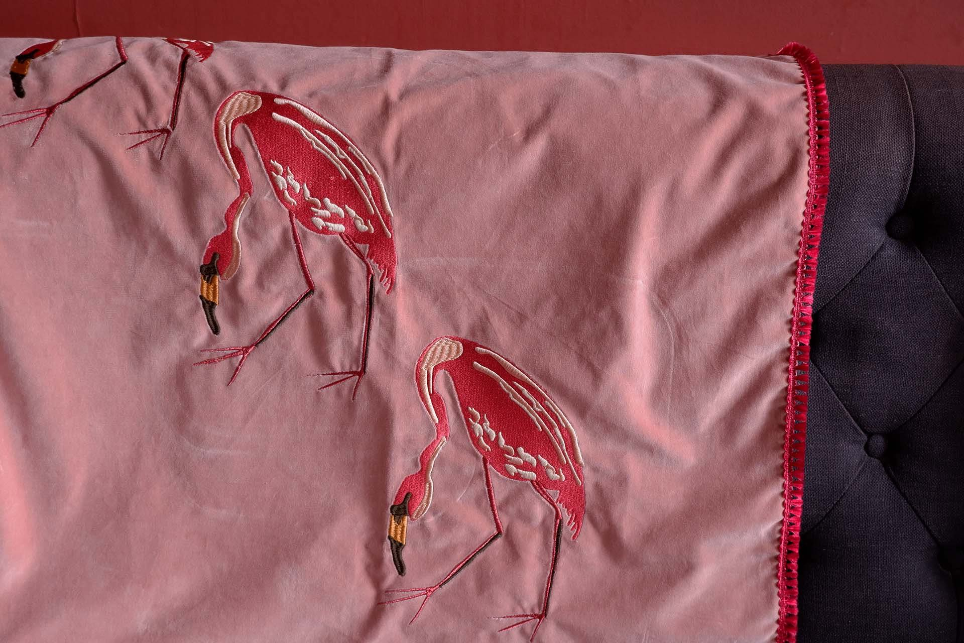 An image of embroidered flamingos onto pink velvet. This sample has then been hemmed with pink fringing